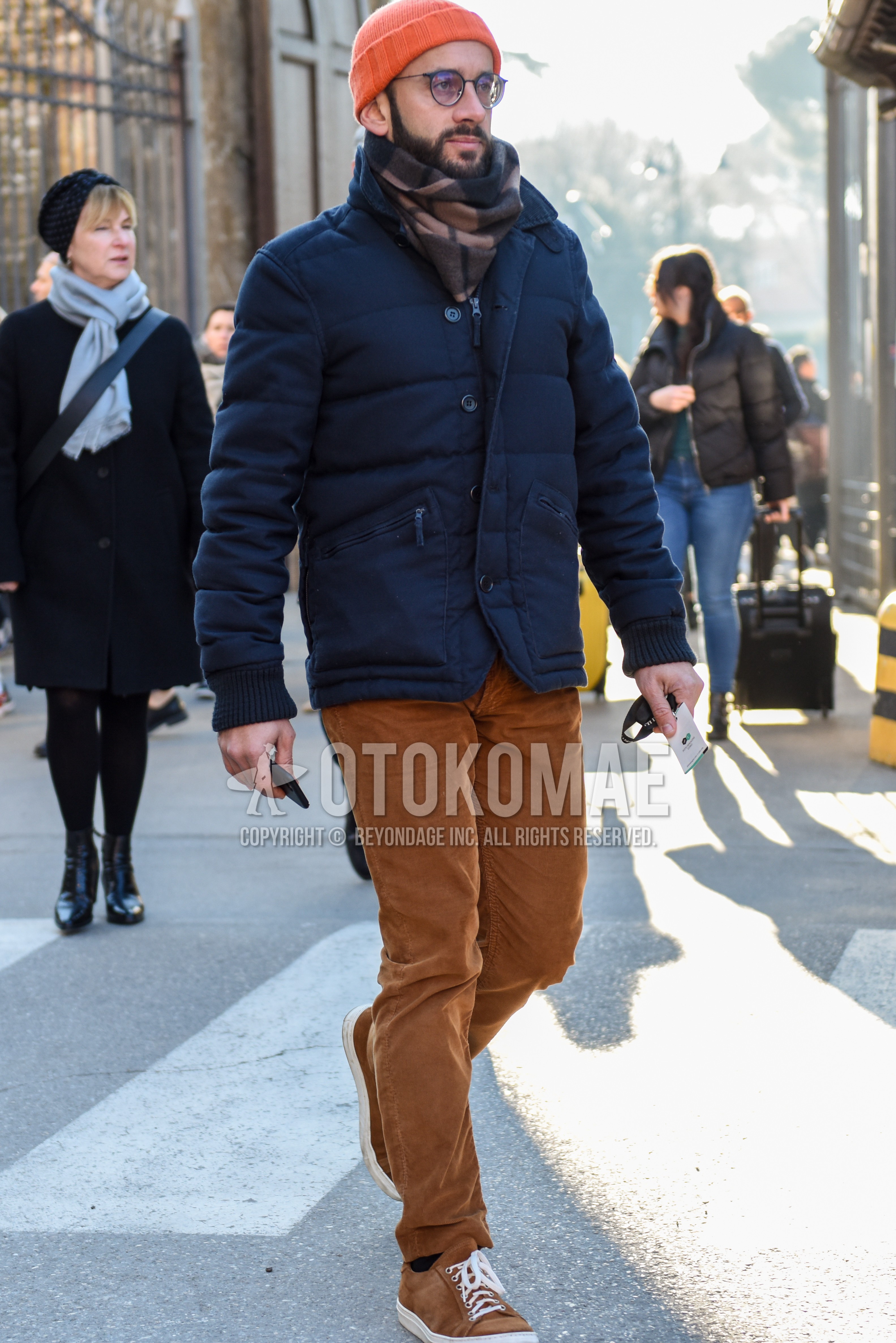 Men's winter outfit with orange plain knit cap, black plain glasses, beige check scarf, navy plain down jacket, brown plain winter pants (corduroy,velour), brown low-cut sneakers.