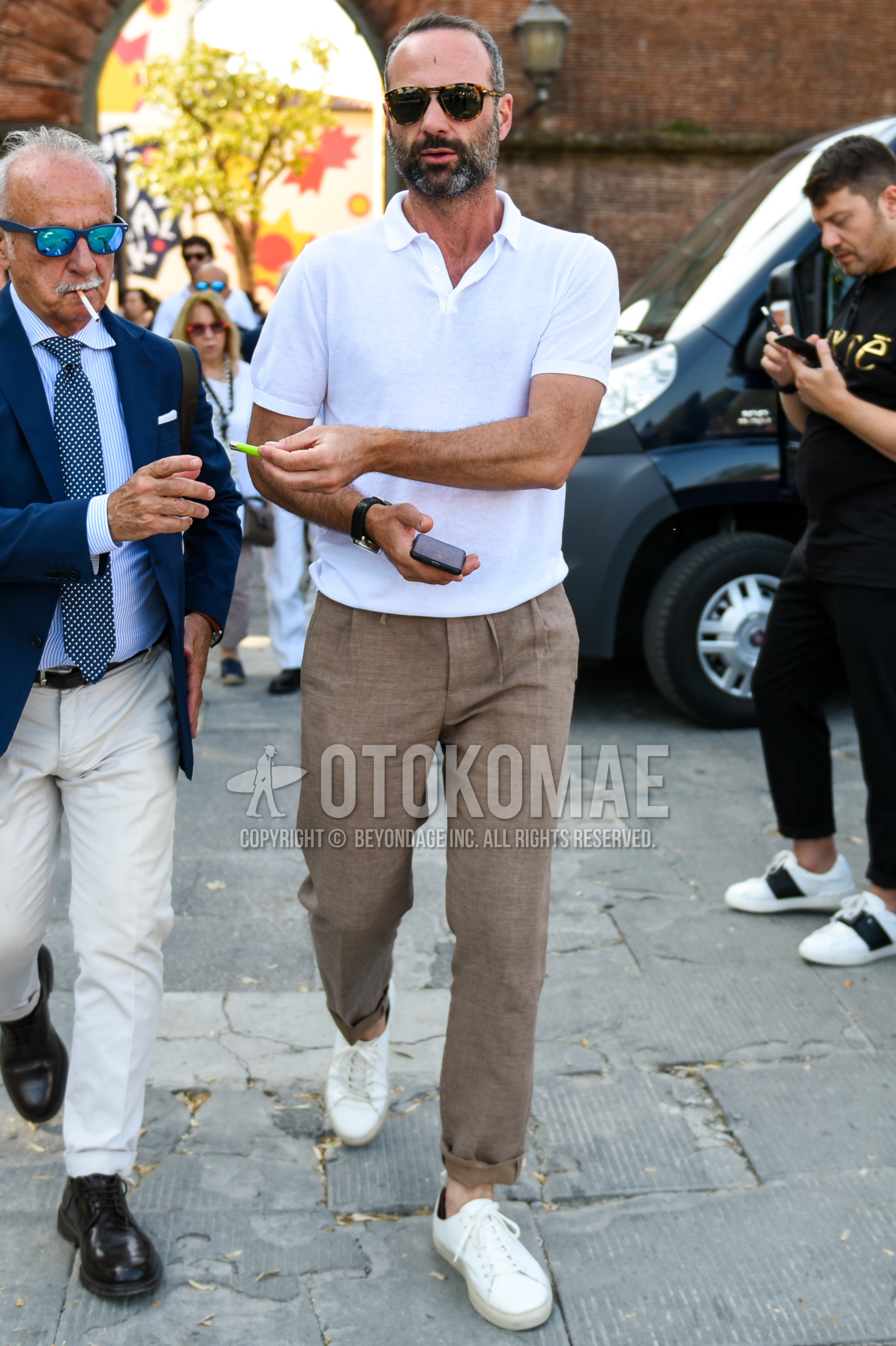 Men's spring summer outfit with brown tortoiseshell sunglasses, white plain polo shirt, brown plain easy pants, brown plain pleated pants, white low-cut sneakers.