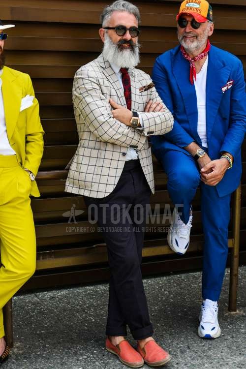 黒無地のサングラス、ベージュチェックのテーラードジャケット、白無地のシャツ、グレー無地のスラックス、オレンジ無地のエスパドリーユ、レッドネクタイのネクタイを合わせた春秋のメンズコーデ・着こなし。