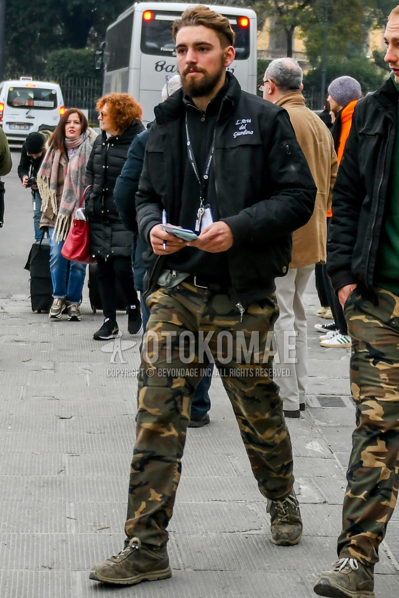 Men's winter outfit with black plain M-65, black plain outerwear, olive green camouflage cargo pants, olive green low-cut sneakers.