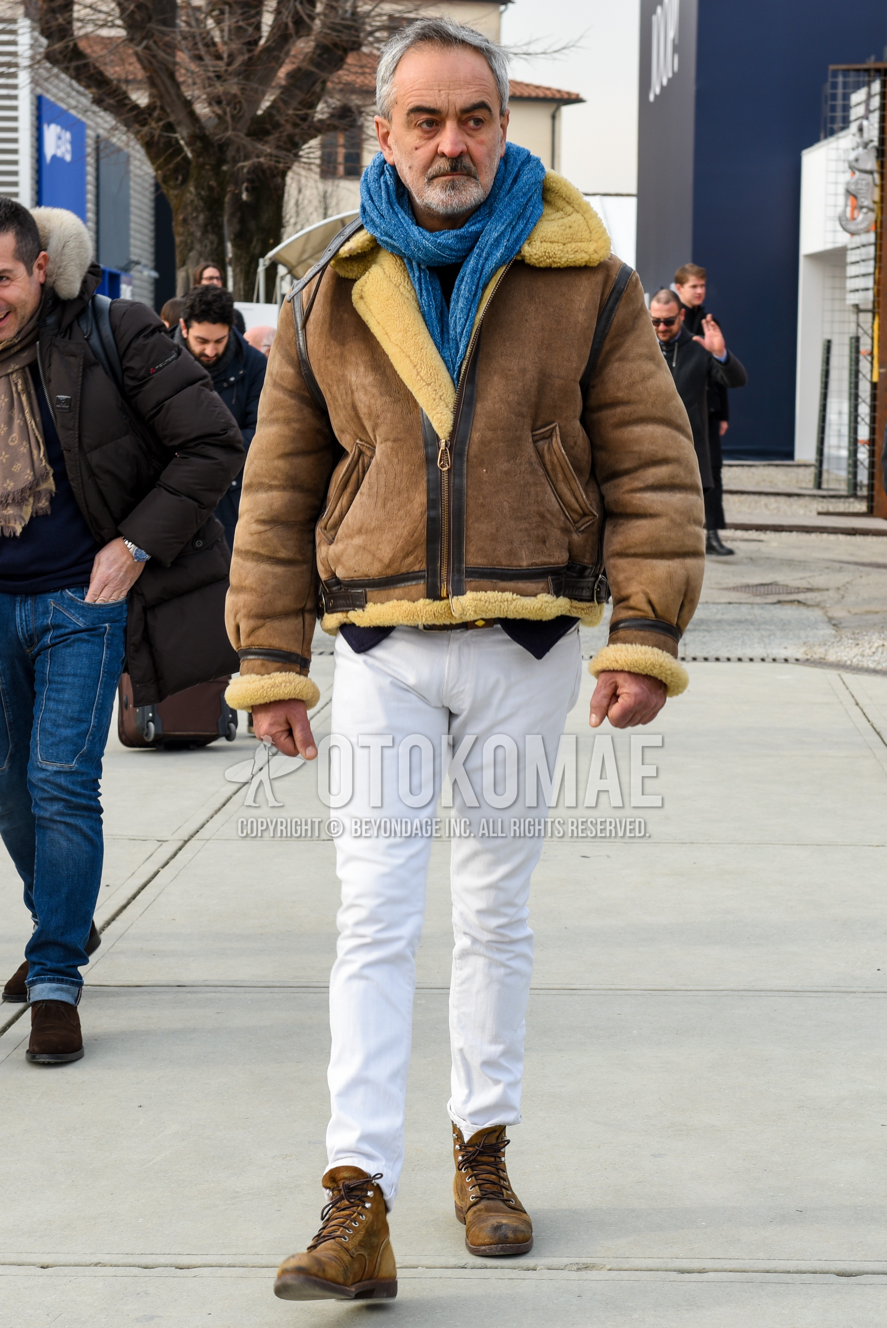 Men's autumn winter outfit with light blue plain scarf, brown plain leather jacket, brown plain military jacket, white plain cotton pants, brown work boots.