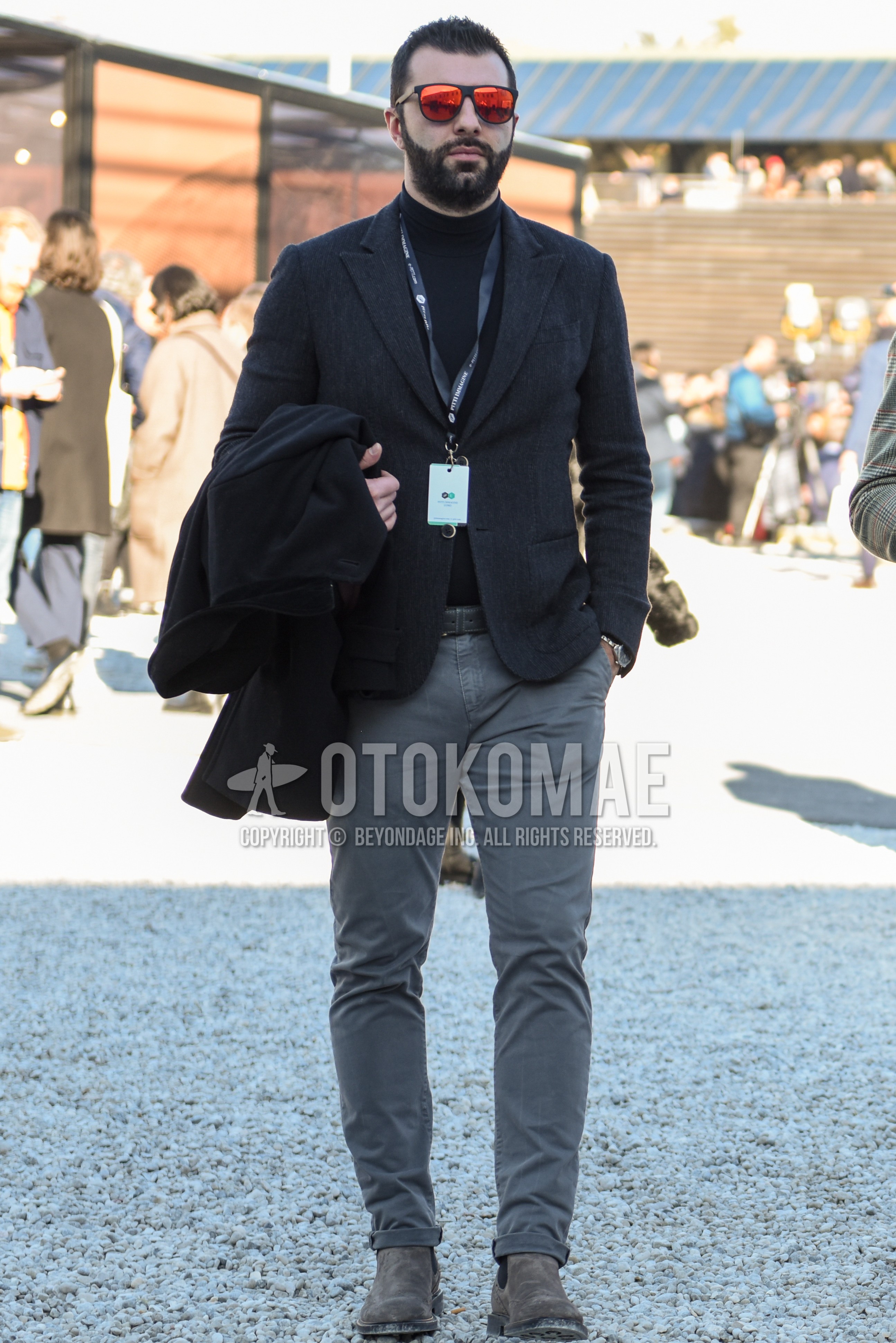 Men's spring autumn outfit with black plain sunglasses, dark gray plain tailored jacket, black plain turtleneck knit, dark gray plain leather belt, gray plain chinos, beige side-gore boots.