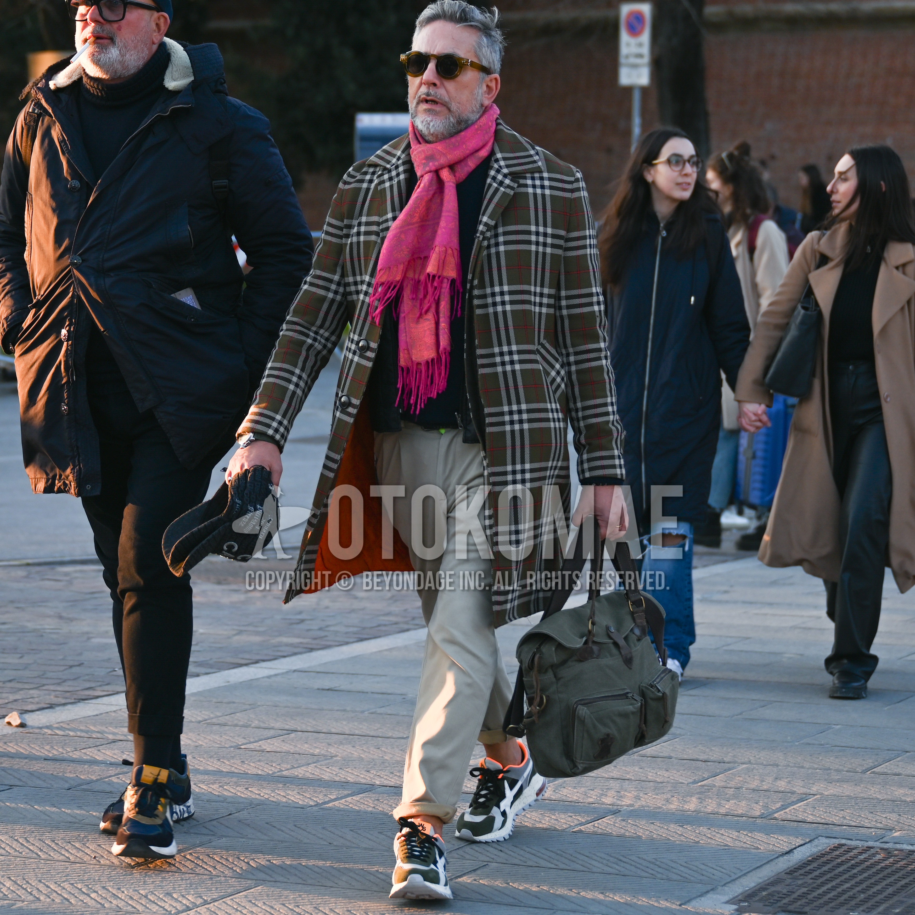 Men's autumn winter outfit with brown tortoiseshell sunglasses, multi-color whole pattern scarf, brown plain stenkarrer coat, beige plain ankle pants, multi-color low-cut sneakers.