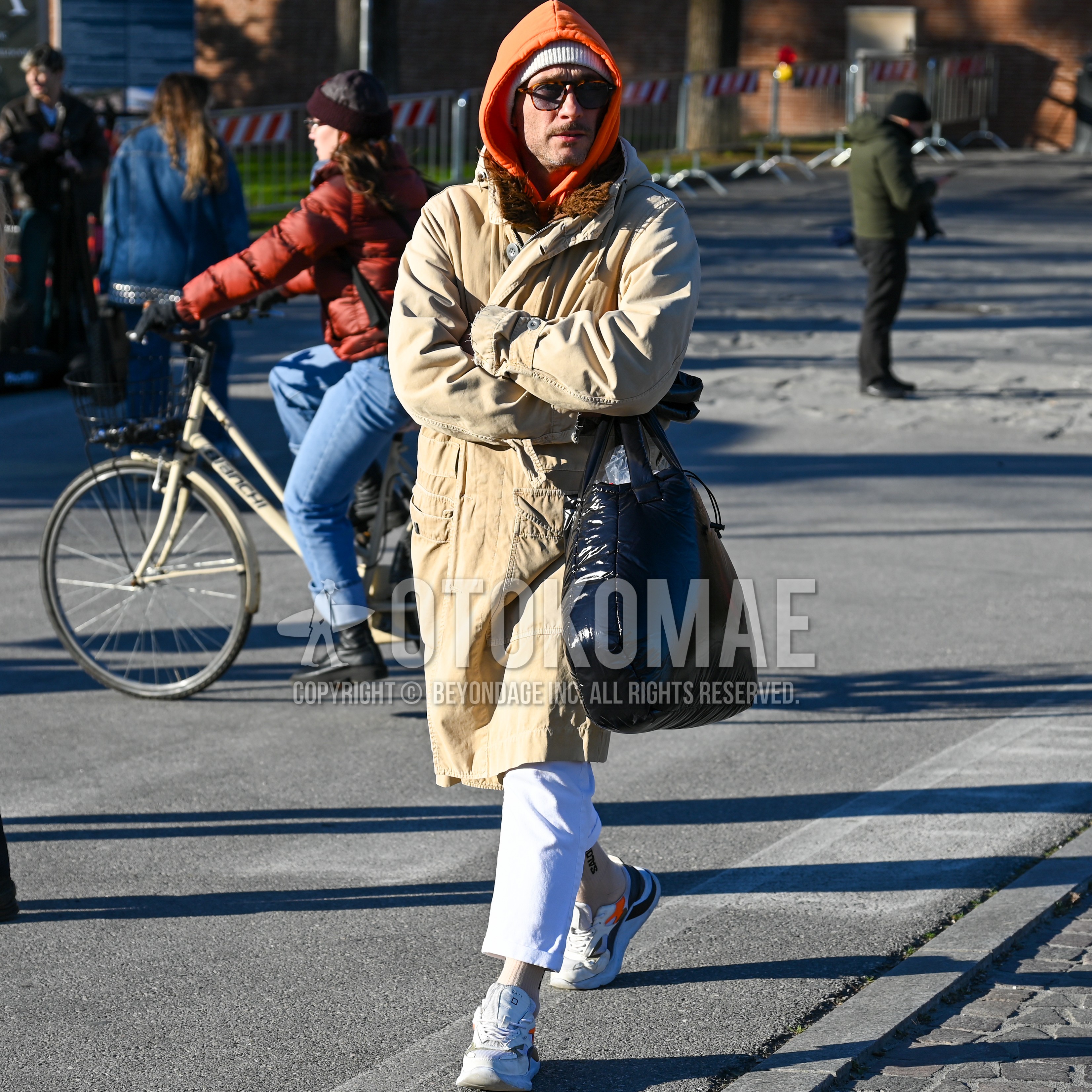 Men's winter outfit with white plain knit cap, brown plain sunglasses, beige plain trench coat, white plain chinos, beige plain socks, white low-cut sneakers.