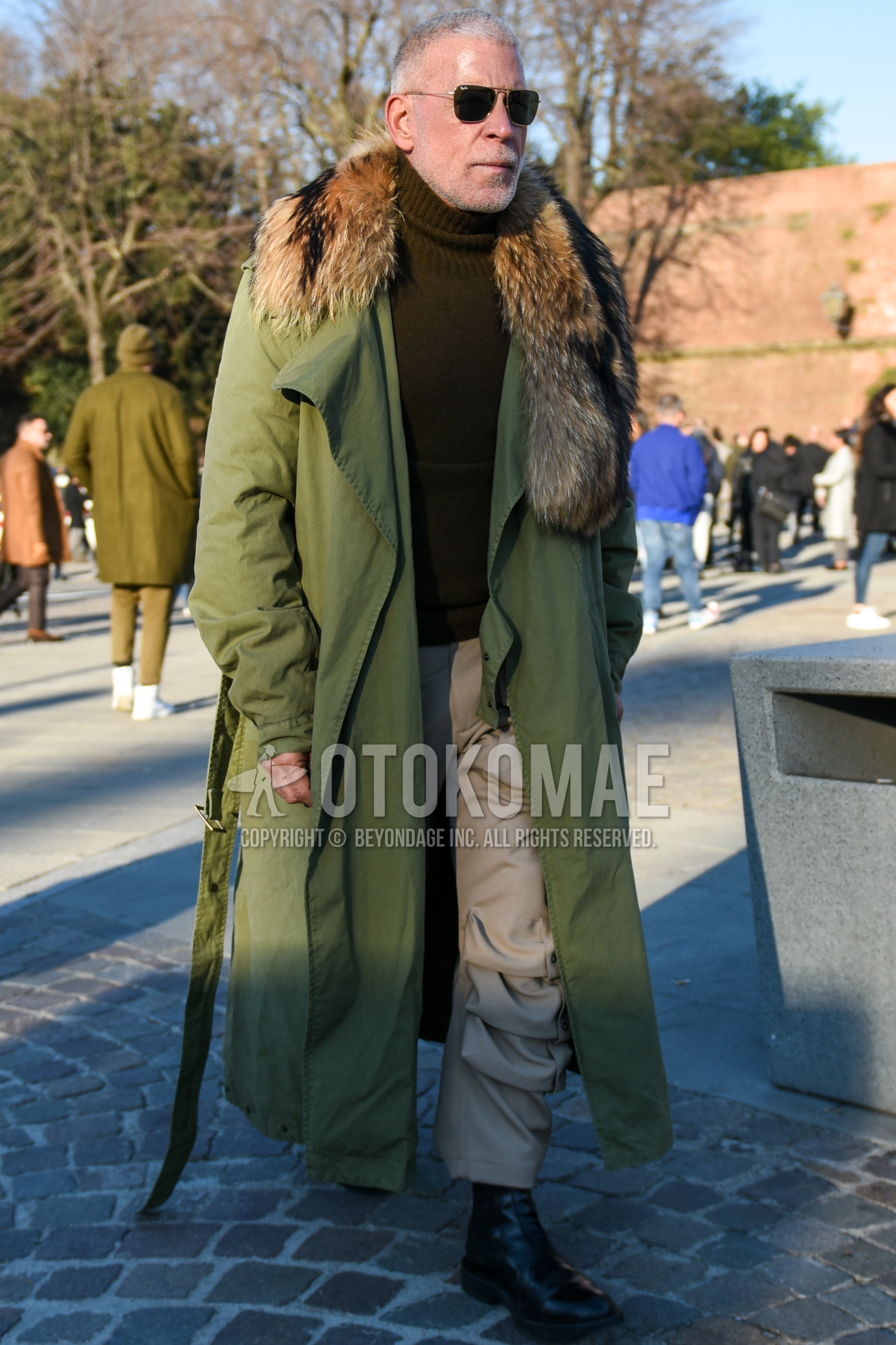 Men's autumn winter outfit with silver plain sunglasses, olive green plain outerwear, brown plain turtleneck knit, beige plain cargo pants, beige plain chinos, black side-gore boots.