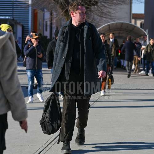 ネイビー無地のトレンチコート、ダークグレー無地のアウター、ネイビー無地のセーター、ブラウン無地の冬パンツ(コーデュロイ,ベロア)、黒ローカットのスニーカー、黒無地のバックパックを合わせた冬のメンズコーデ・着こなし。