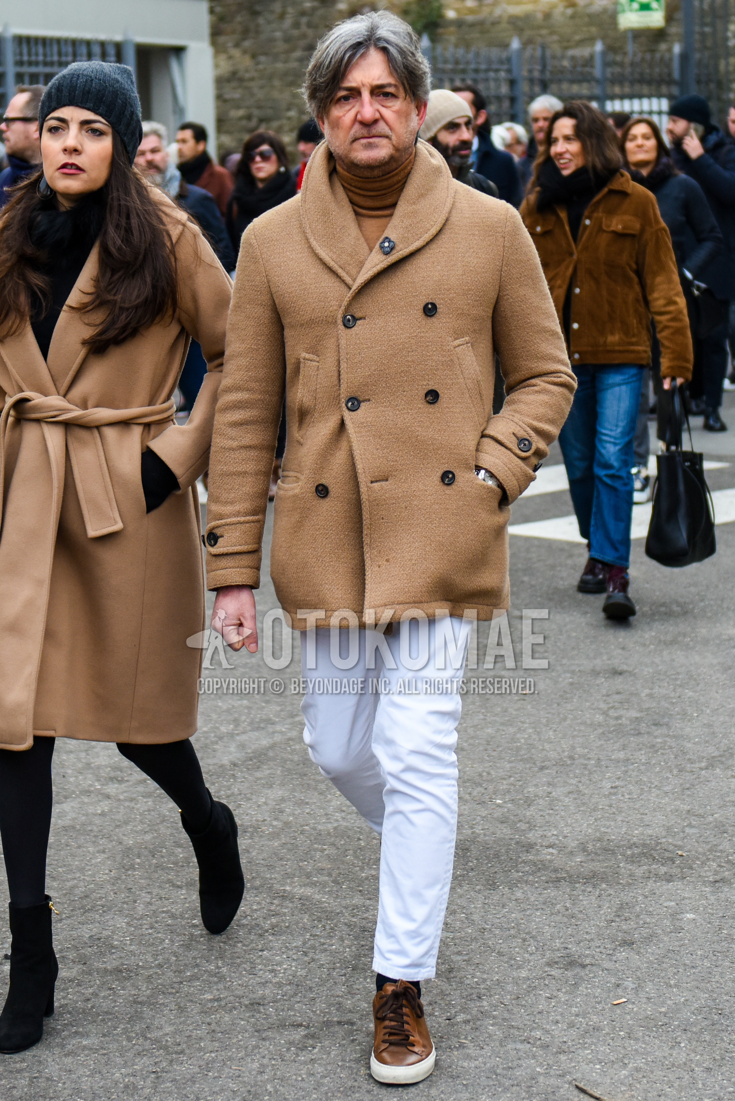 Men's autumn winter outfit with beige plain shawl collar coat, brown plain turtleneck knit, white plain cotton pants, white plain ankle pants, brown low-cut sneakers.