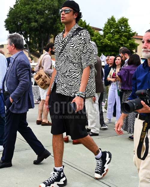 黒無地のキャップ、シルバー無地のサングラス、白ゼブラのシャツ、黒無地のショートパンツ、白ワンポイントのソックス、コンバースの黒ハイカットのスニーカー、黒無地のショルダーバッグを合わせた夏春のメンズコーデ・着こなし。