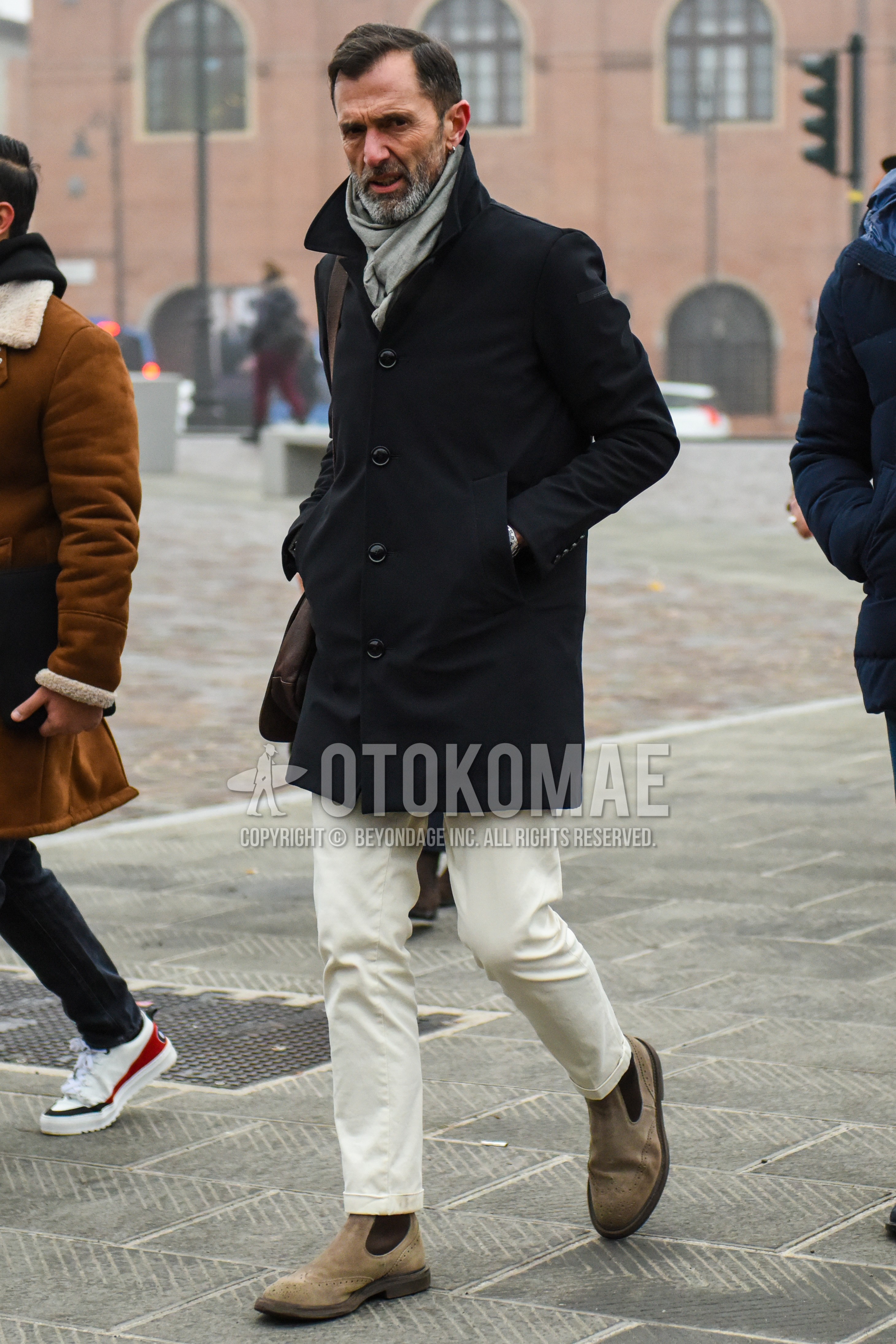 Men's winter outfit with gray plain scarf, black plain stenkarrer coat, white plain chinos, beige side-gore boots, brown plain shoulder bag.