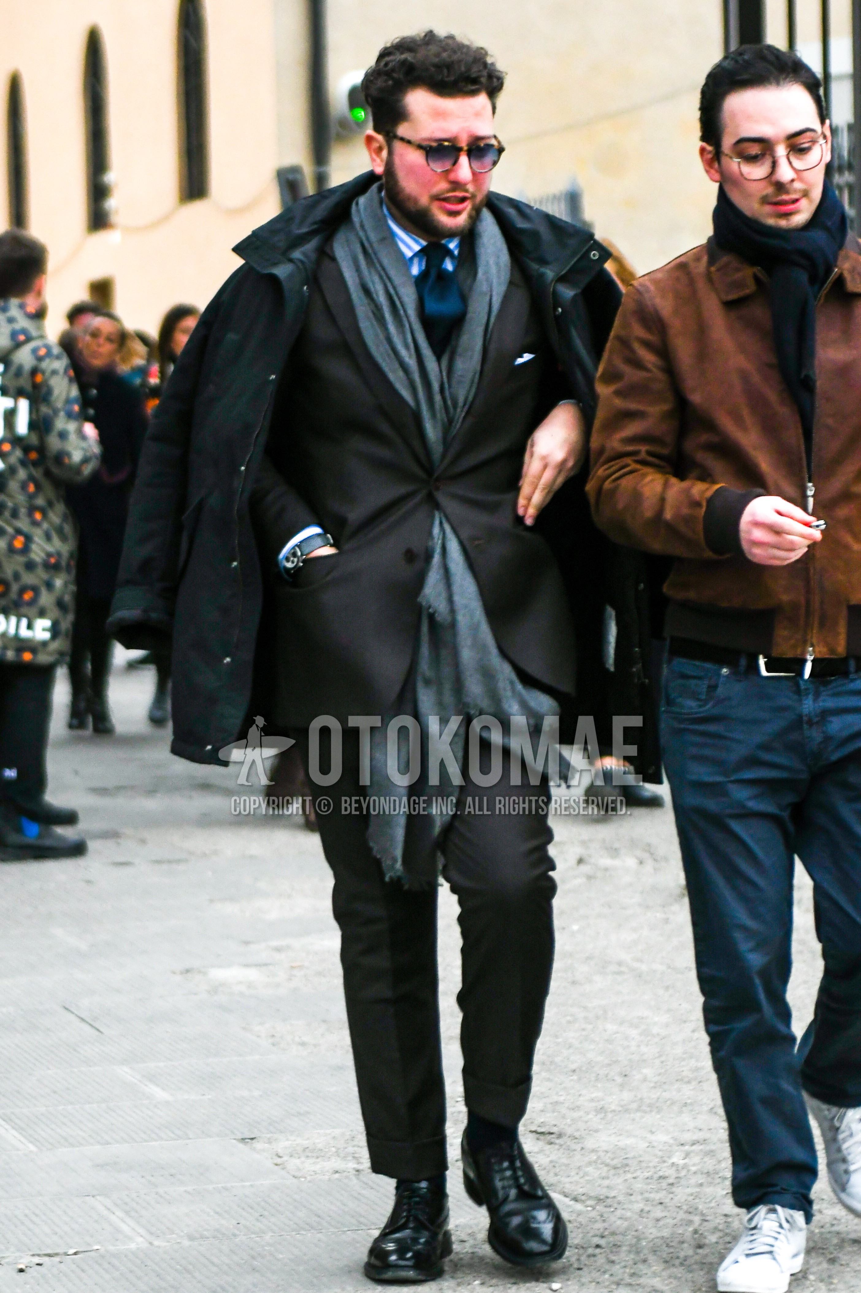 Men's winter outfit with plain sunglasses, gray plain scarf, black plain down jacket, light blue stripes shirt, black wing-tip shoes leather shoes, dark gray plain suit, navy plain necktie.