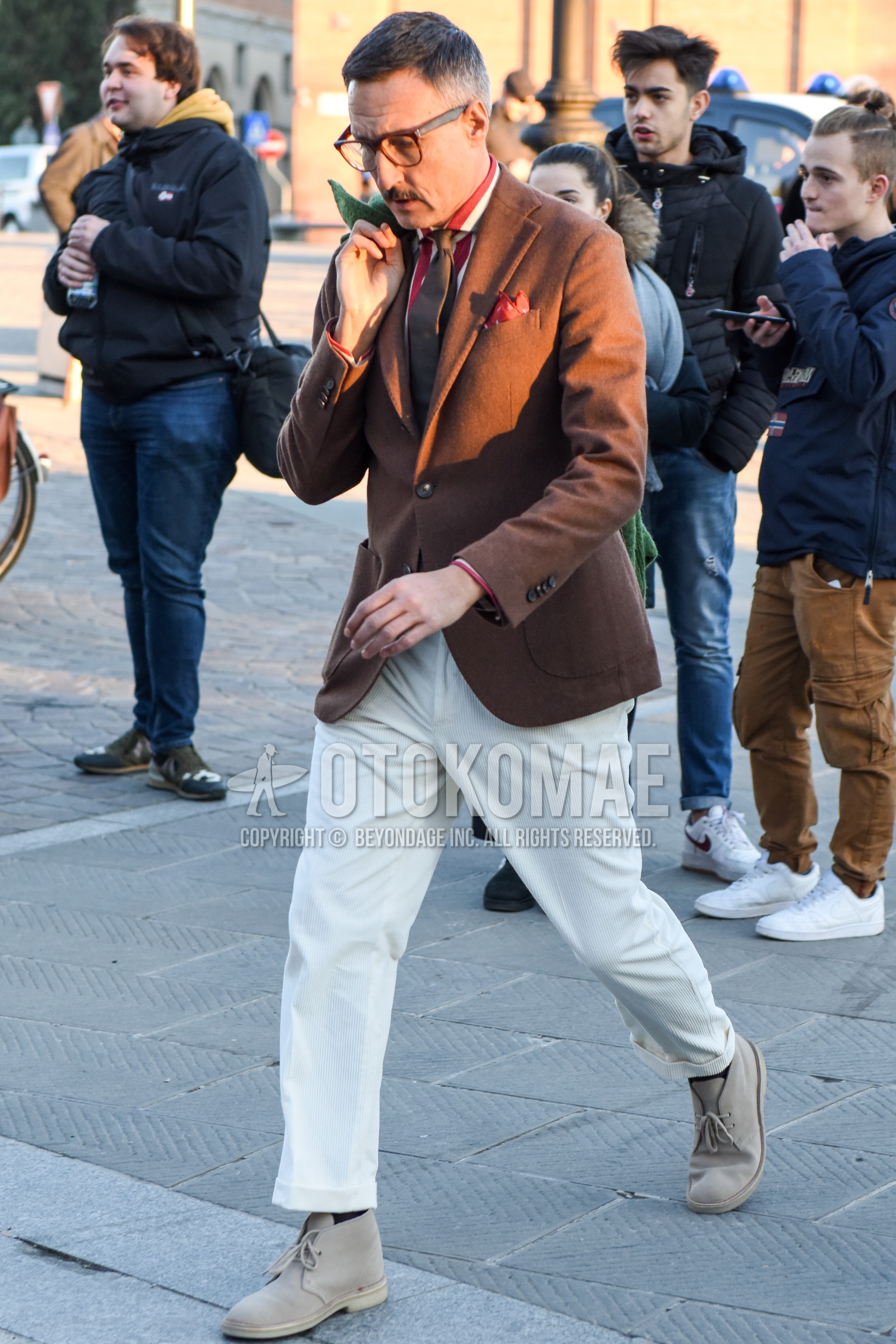 Men's spring autumn outfit with brown tortoiseshell glasses, brown plain tailored jacket, white red stripes shirt, white plain winter pants (corduroy,velour), black plain socks, beige chukka boots, brown plain necktie.