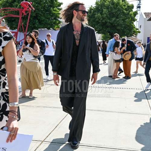 黒無地のサングラス、黒トップス/インナーのシャツ、黒コインローファーの革靴、黒無地のスーツを合わせた夏春のメンズコーデ・着こなし。