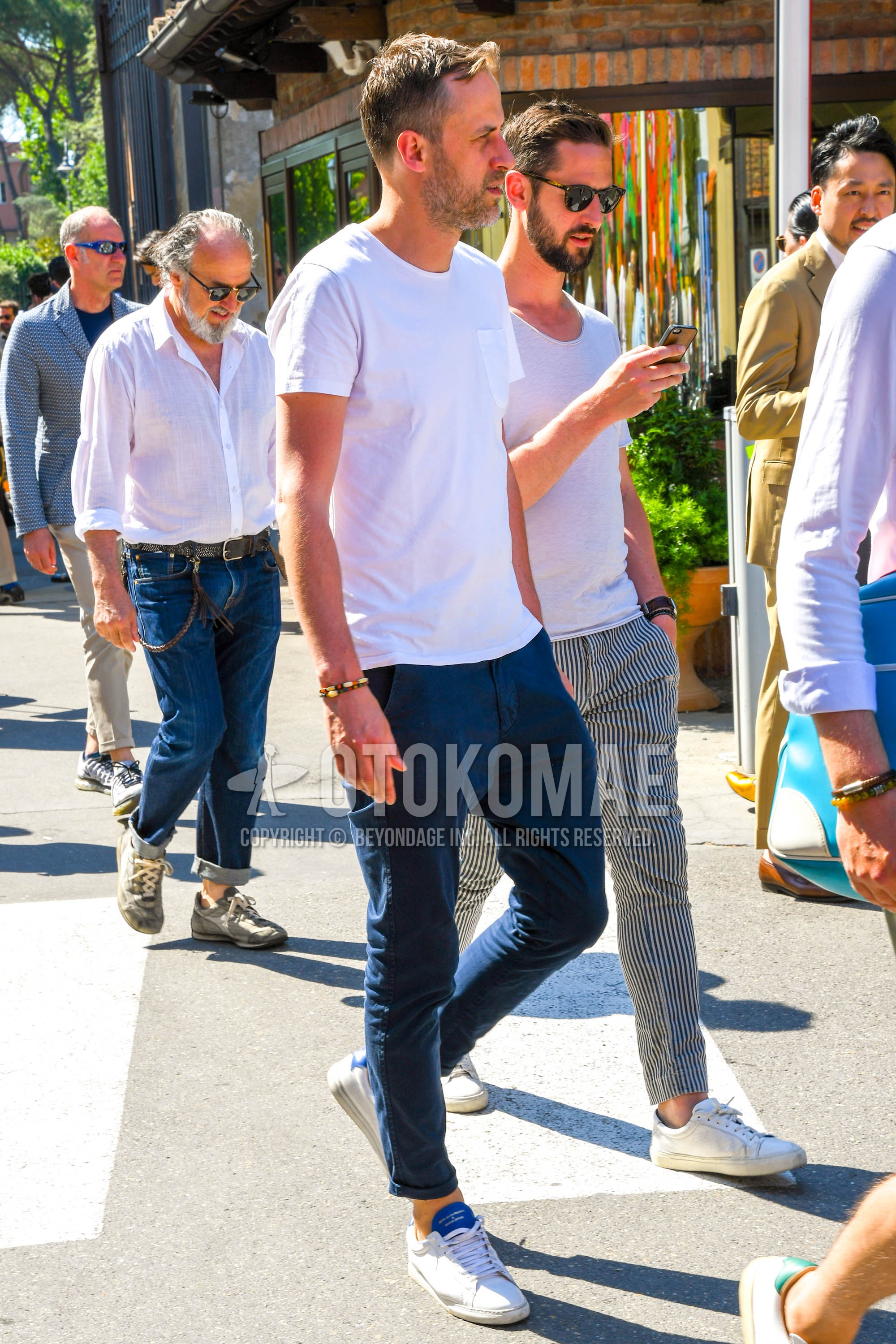 Men's summer outfit with white plain t-shirt, navy plain chinos, white low-cut sneakers.