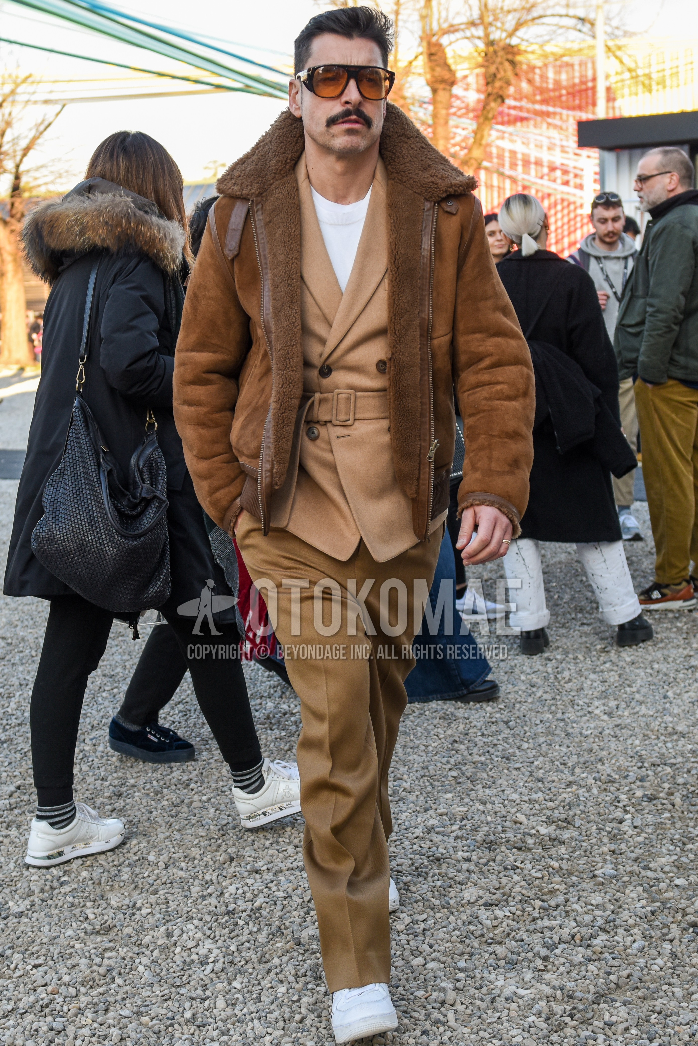 Men's autumn winter outfit with brown tortoiseshell sunglasses, brown plain leather jacket, brown plain military jacket, beige plain tailored jacket, white plain sweater, beige plain chinos, beige plain slacks, white low-cut sneakers.