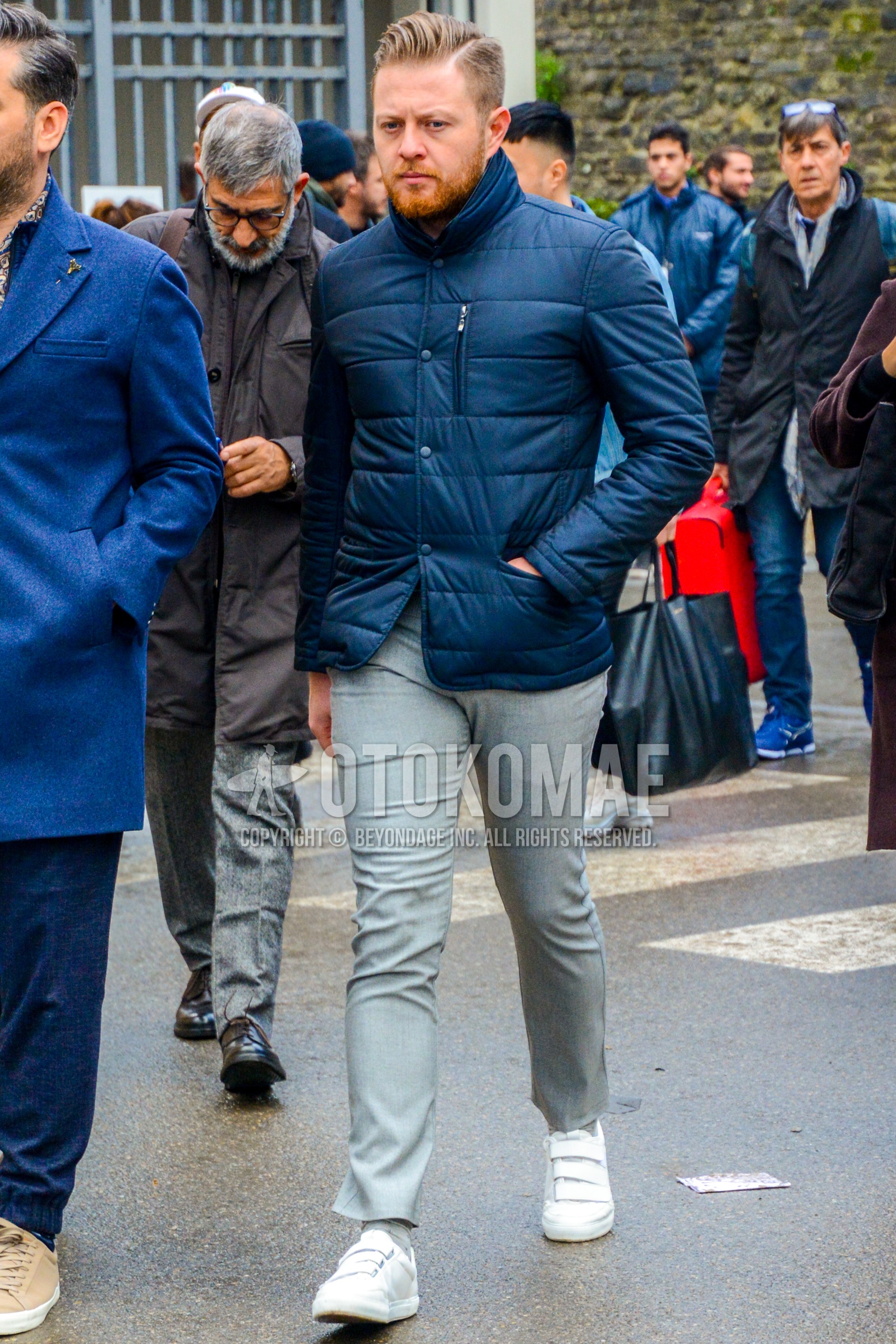 Men's winter outfit with blue plain down jacket, gray plain ankle pants, gray plain socks, white low-cut sneakers.
