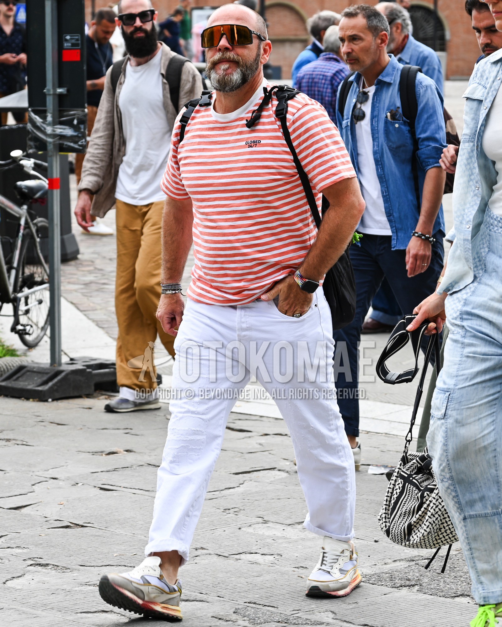 Men's spring summer outfit with brown plain sunglasses, red horizontal stripes t-shirt, white plain denim/jeans, white low-cut sneakers, black plain backpack.