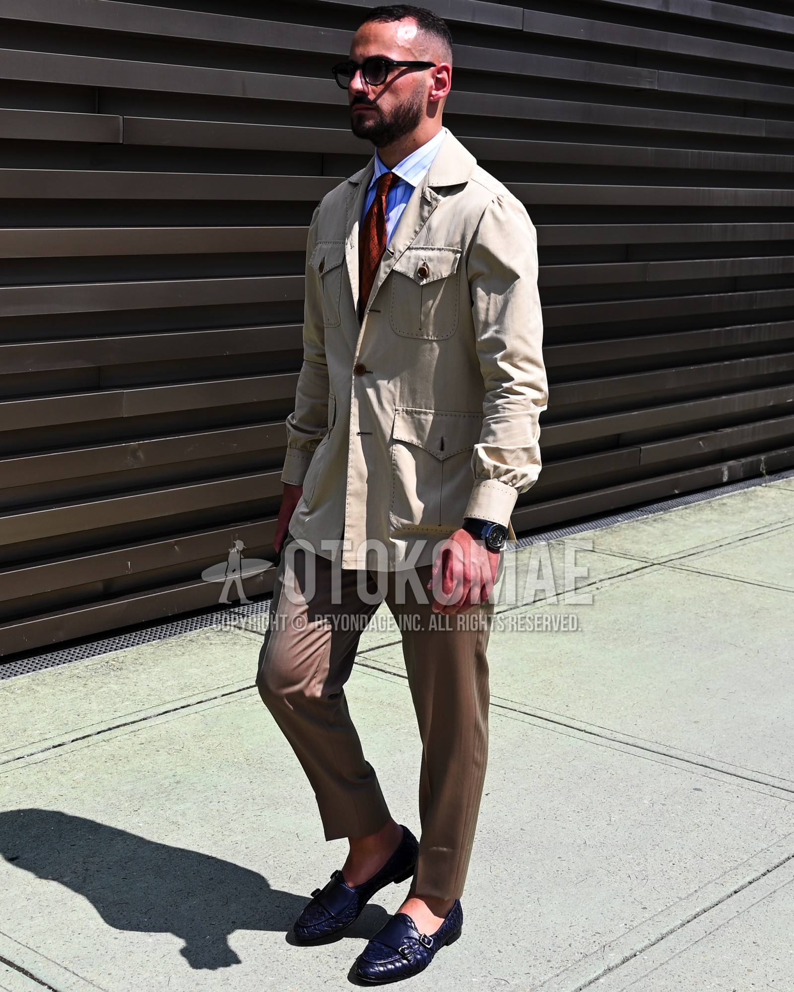 Men's spring summer autumn outfit with black plain sunglasses, beige plain safari jacket, white plain shirt, brown plain slacks, black  loafers leather shoes, red plain necktie.