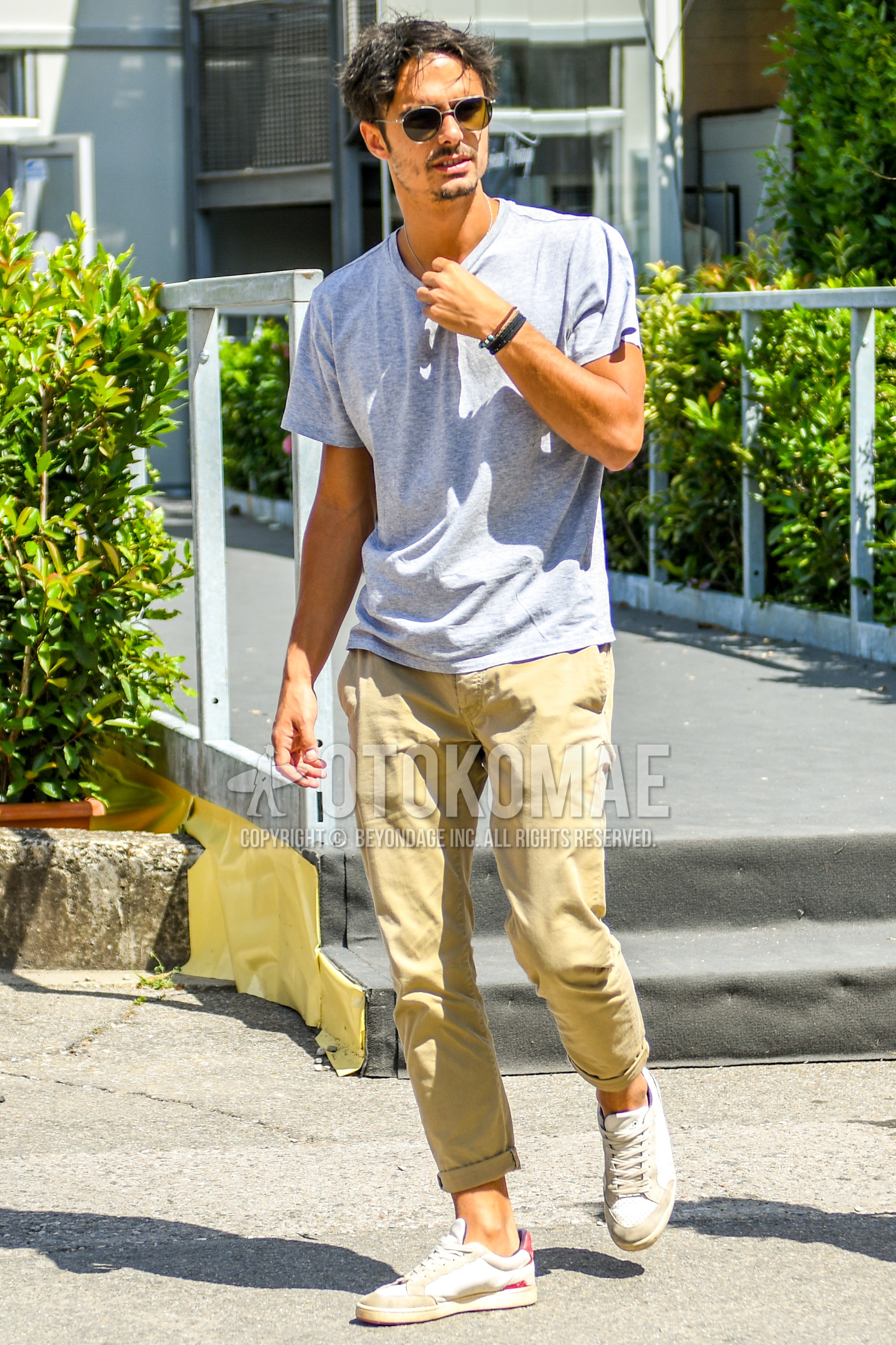 Men's summer outfit with plain sunglasses, gray plain t-shirt, beige plain chinos, white low-cut sneakers.