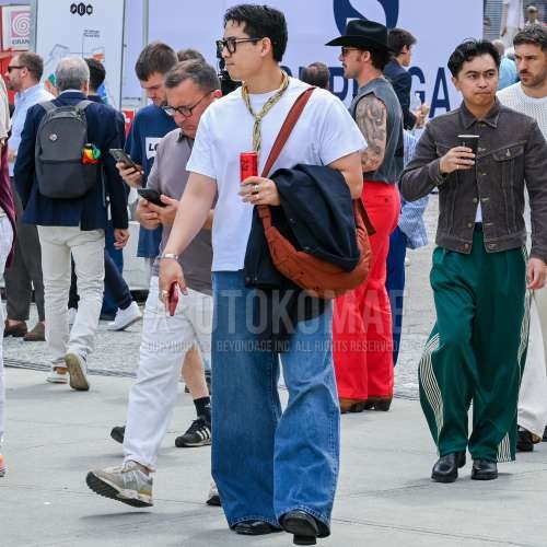 黒無地のメガネ、イエローストールのバンダナ/ネッカチーフ、黒無地のアウター、白無地のTシャツ、ブルー無地のデニム/ジーンズ、黒のブーツ、オレンジ無地のショルダーバッグを合わせた夏春のメンズコーデ・着こなし。