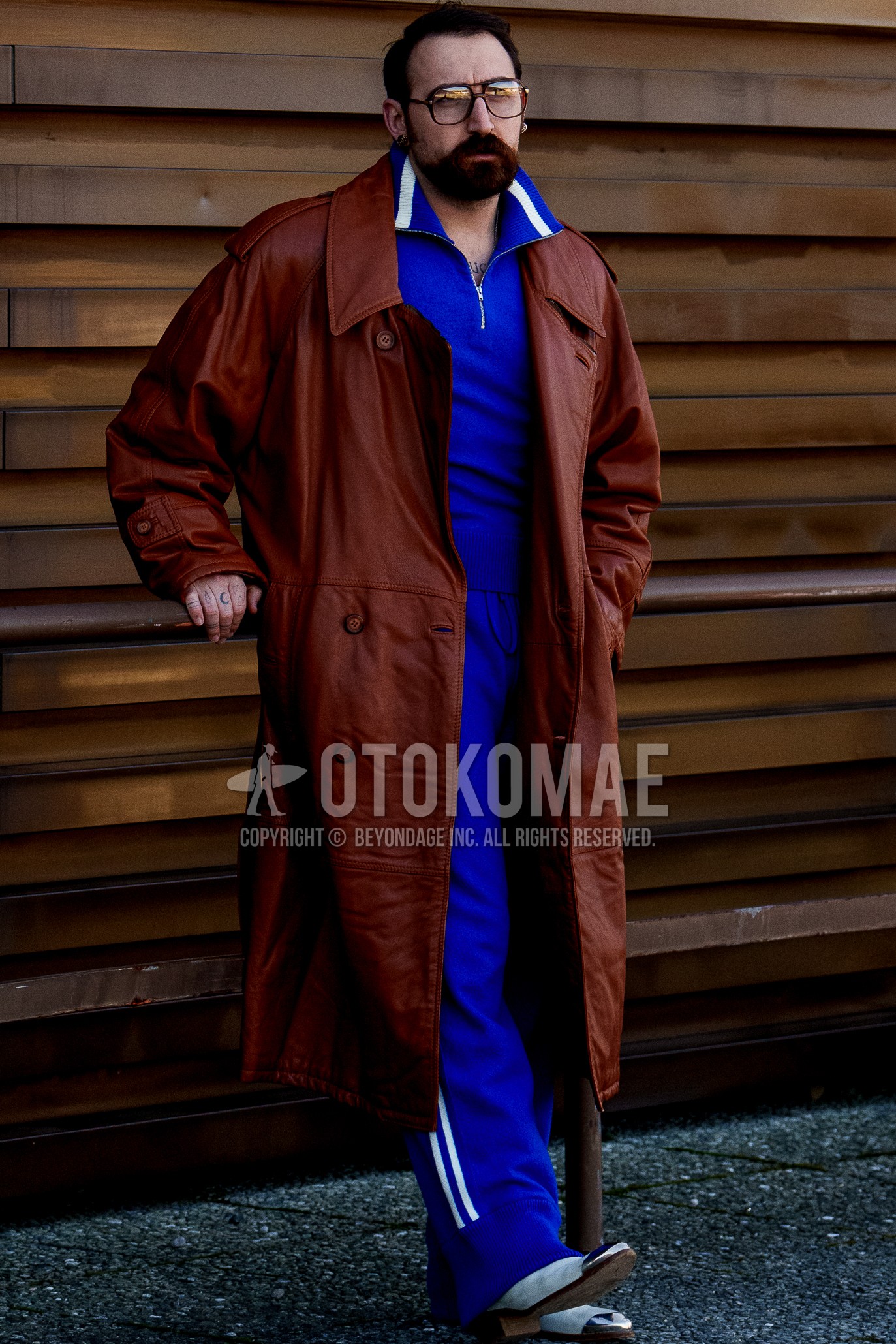 Men's spring winter outfit with brown plain glasses, brown plain trench coat, white  leather shoes, blue plain casual setup.