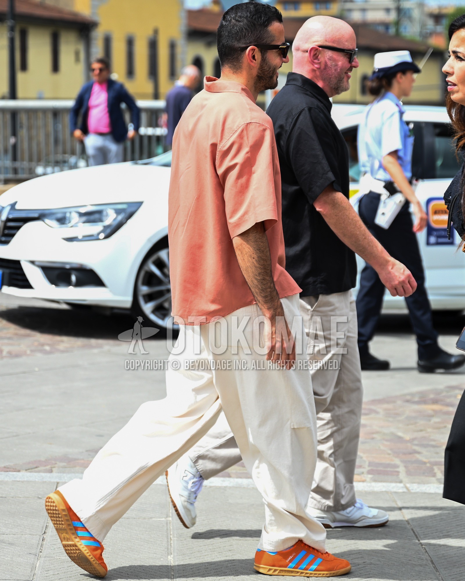 Men's spring summer outfit with orange plain shirt, white plain wide pants, orange low-cut sneakers.