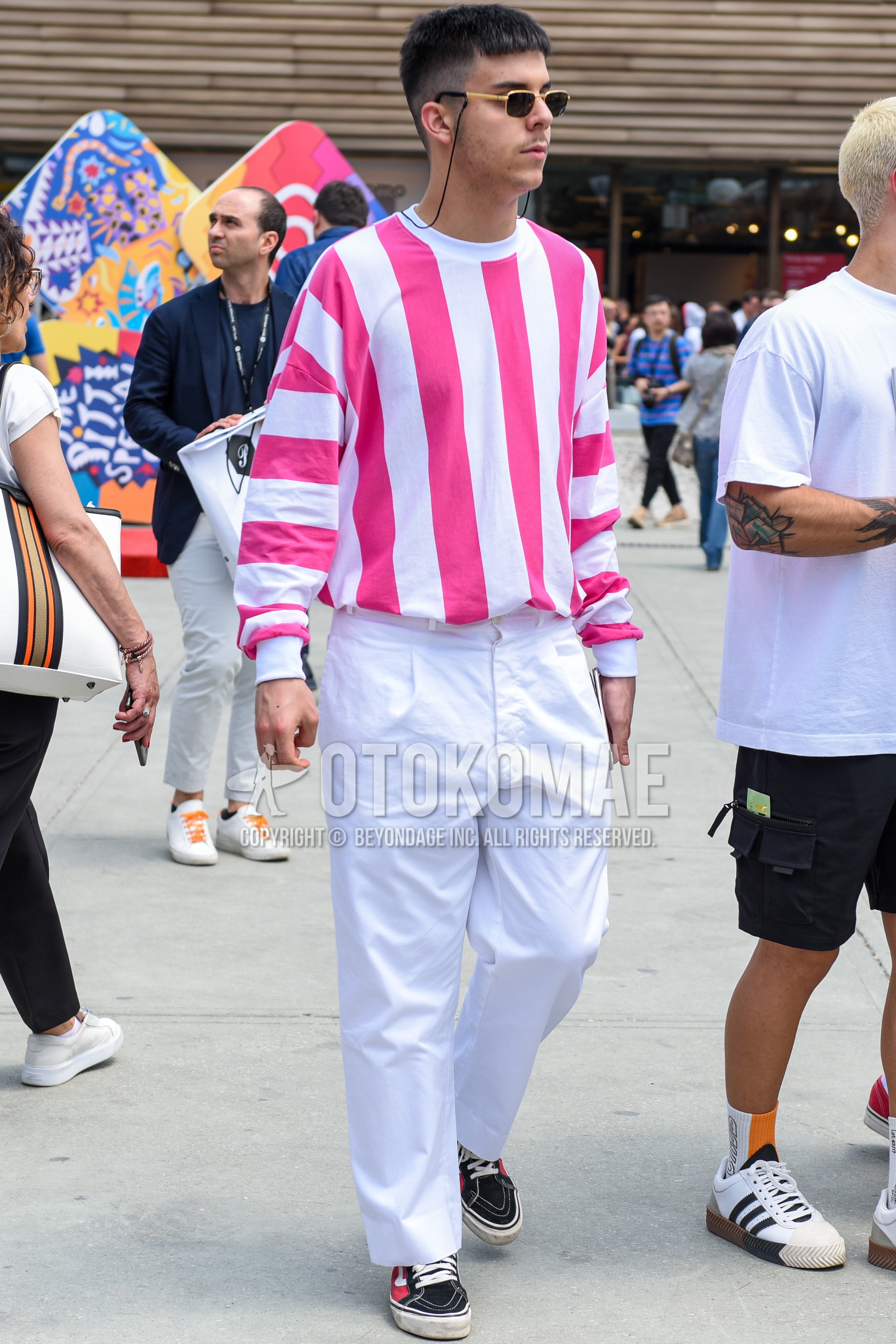 Men's spring autumn outfit with gold black plain sunglasses, pink white stripes sweater, white plain wide pants, black pink low-cut sneakers.