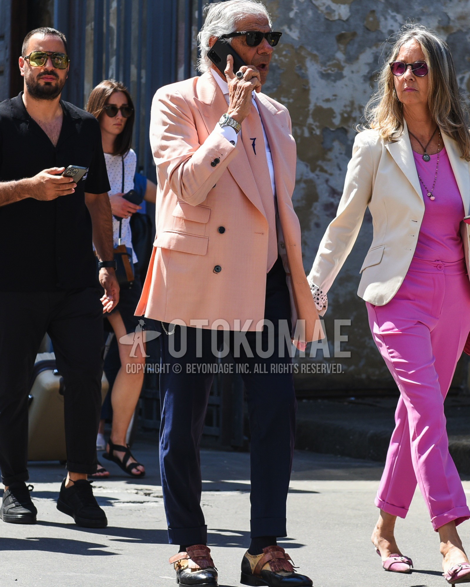 Men's spring summer outfit with black plain sunglasses, pink plain tailored jacket, white plain shirt, navy plain slacks, black plain socks, blue beige  leather shoes, pink one point necktie.