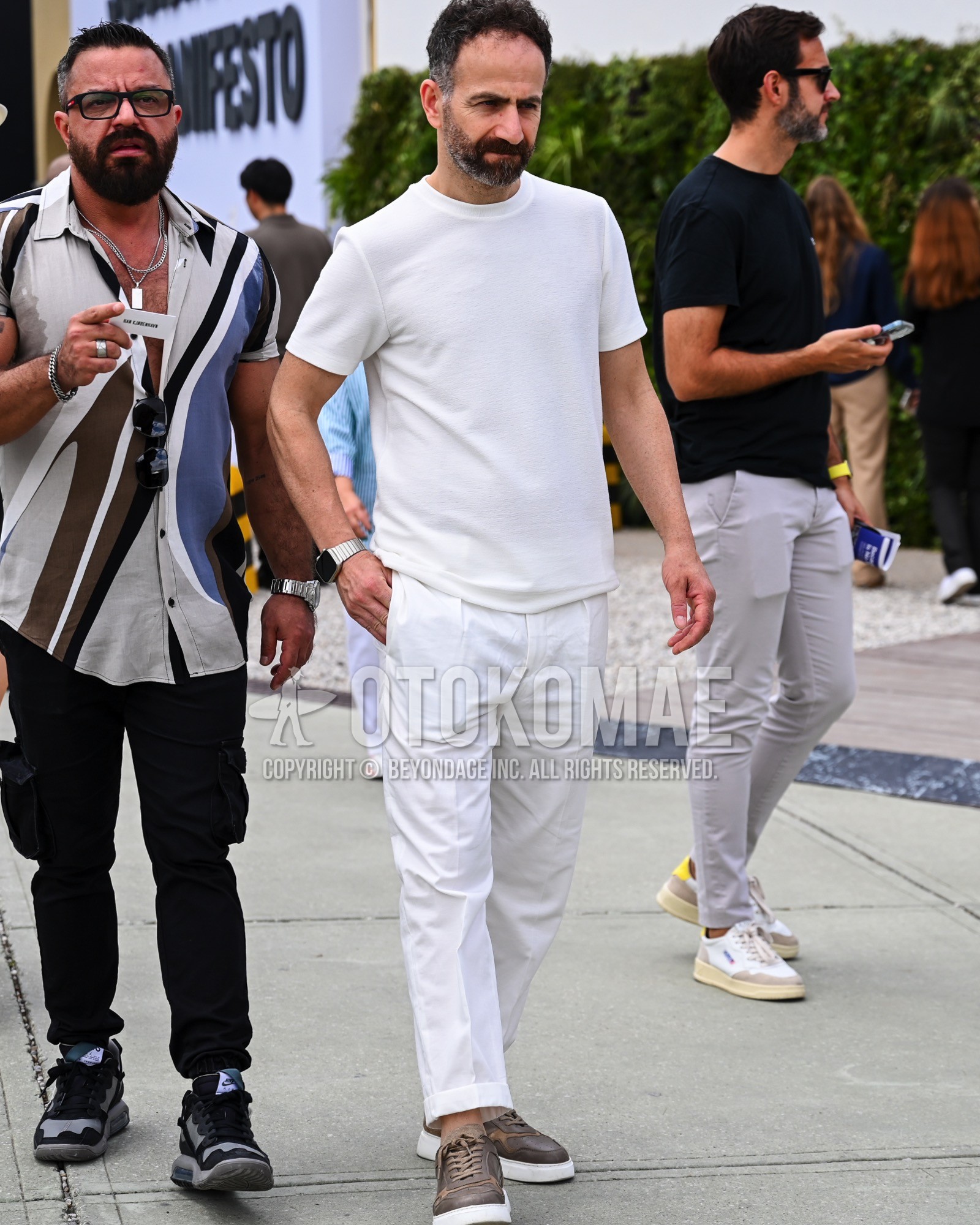 Men's spring summer outfit with white plain t-shirt, white plain pleated pants, brown low-cut sneakers.
