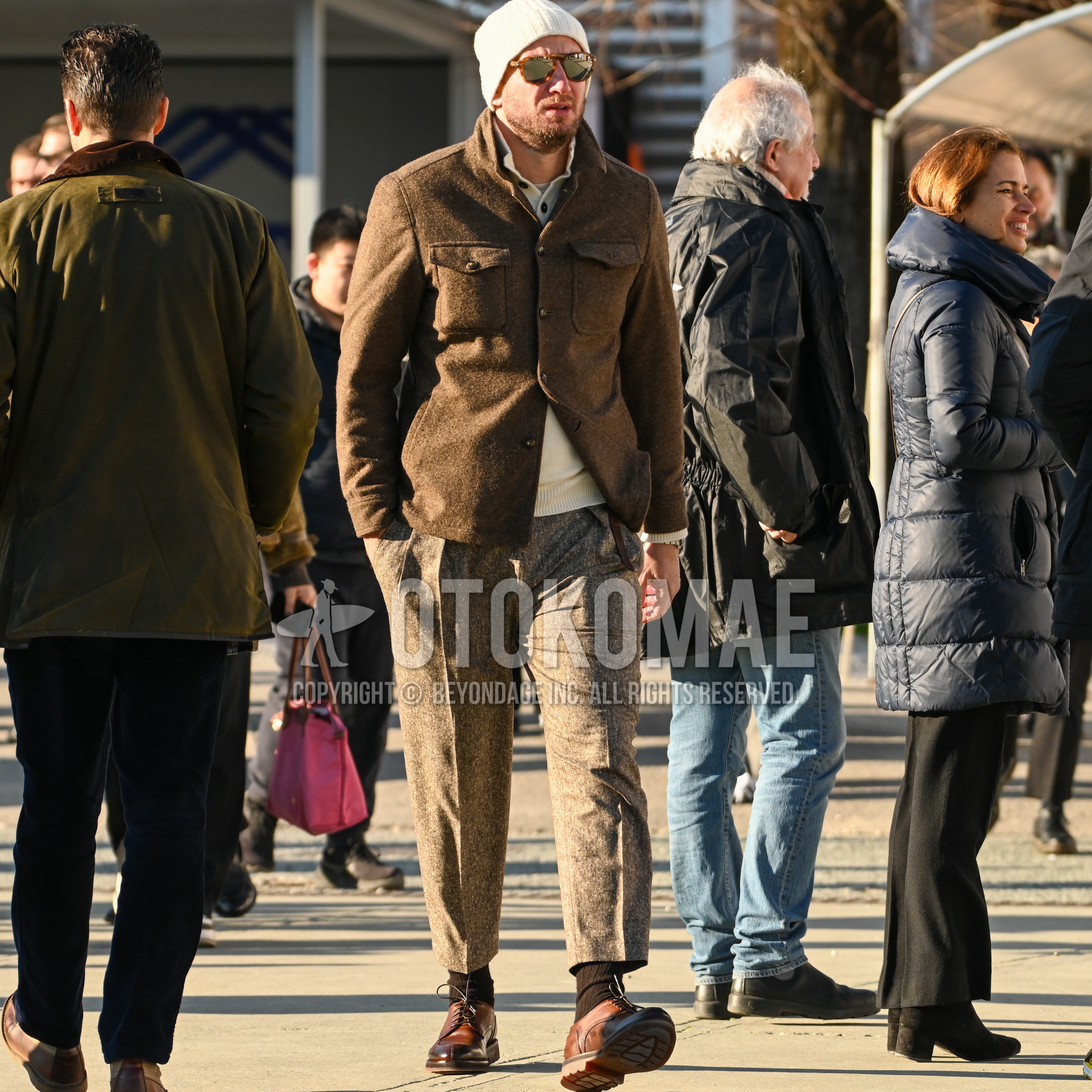 Men's autumn winter outfit with white plain knit cap, tortoiseshell sunglasses, brown plain shirt jacket, beige plain sweater, gray plain ankle pants, black plain socks, brown u-tip shoes leather shoes.