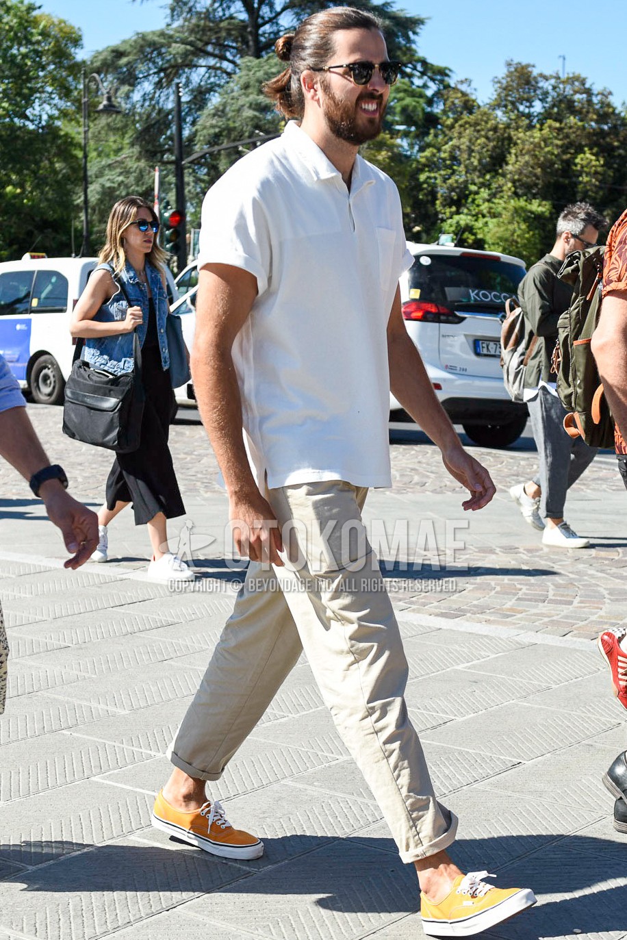 Men's summer outfit with black plain sunglasses, white plain polo shirt, beige plain chinos, yellow low-cut sneakers.