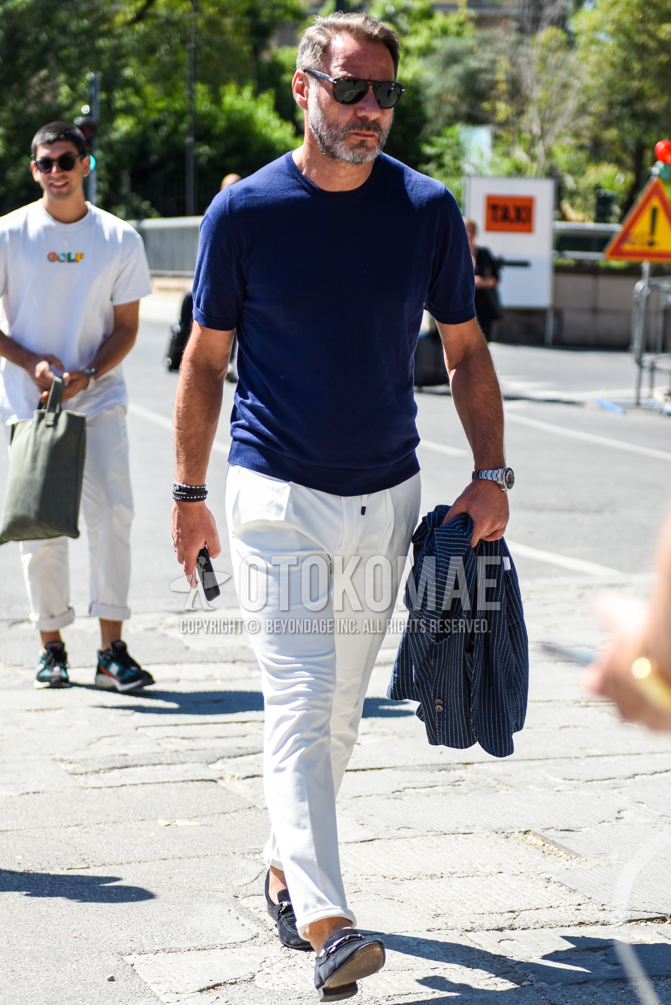 Men's summer outfit with brown tortoiseshell sunglasses, navy plain t-shirt, white plain cotton pants, navy bit loafers leather shoes.