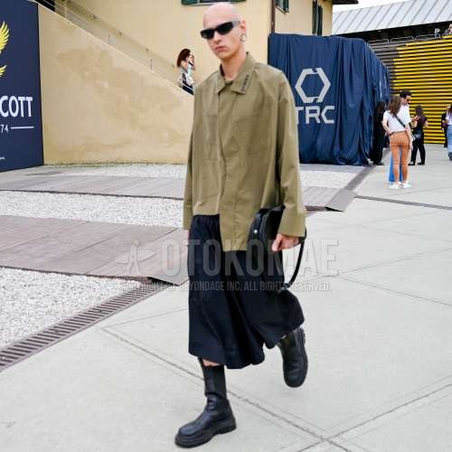 黒無地のサングラス、ベージュ無地のシャツ、ダークグレー無地のボトムス、黒のブーツ、黒無地のバッグを合わせた春夏のメンズコーデ・着こなし。