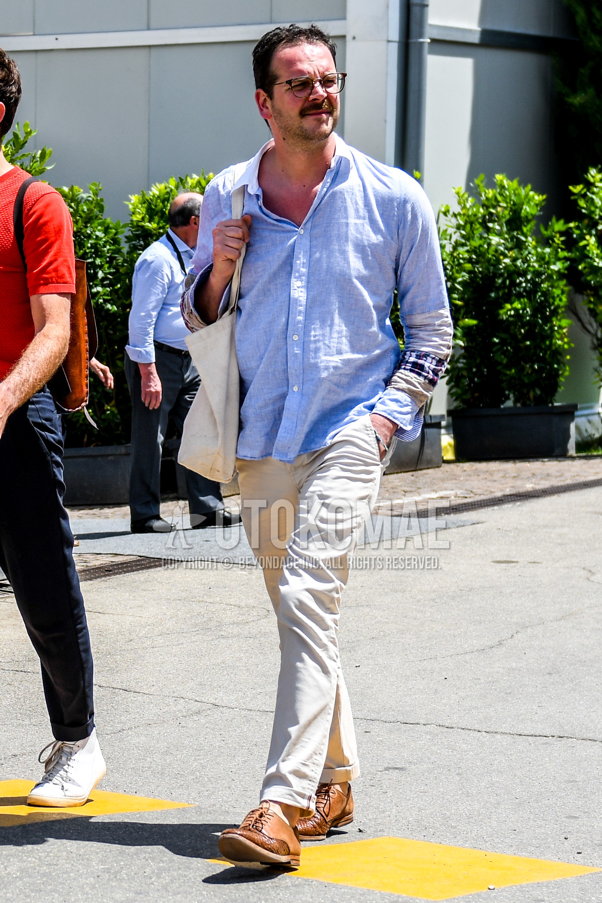 Men's spring summer outfit with plain glasses, blue plain shirt, beige plain chinos, brown plain toe leather shoes.