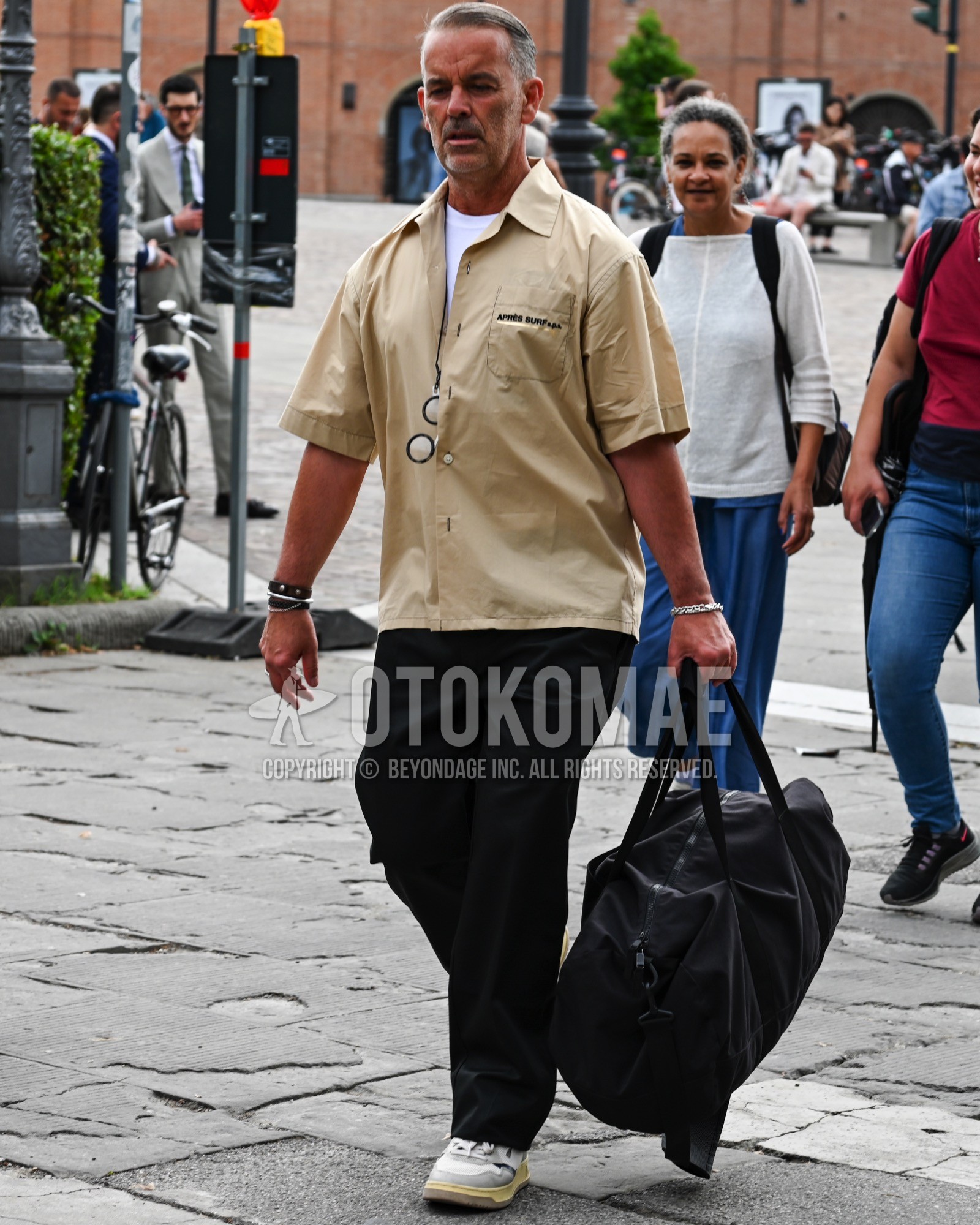 Men's spring summer outfit with beige plain shirt, white plain t-shirt, black plain cargo pants, black plain boston bag.