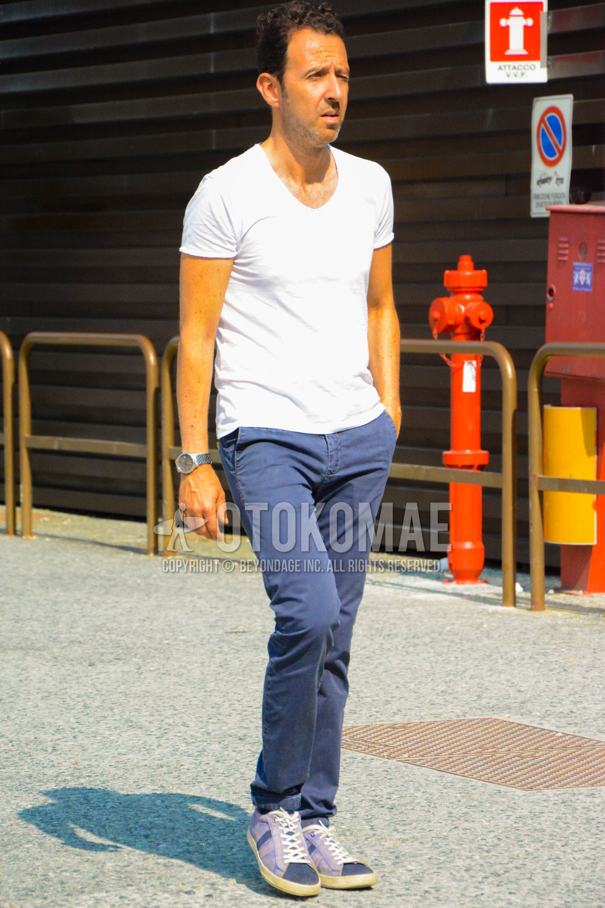 Men's spring summer outfit with white plain t-shirt, navy plain chinos, navy low-cut sneakers.