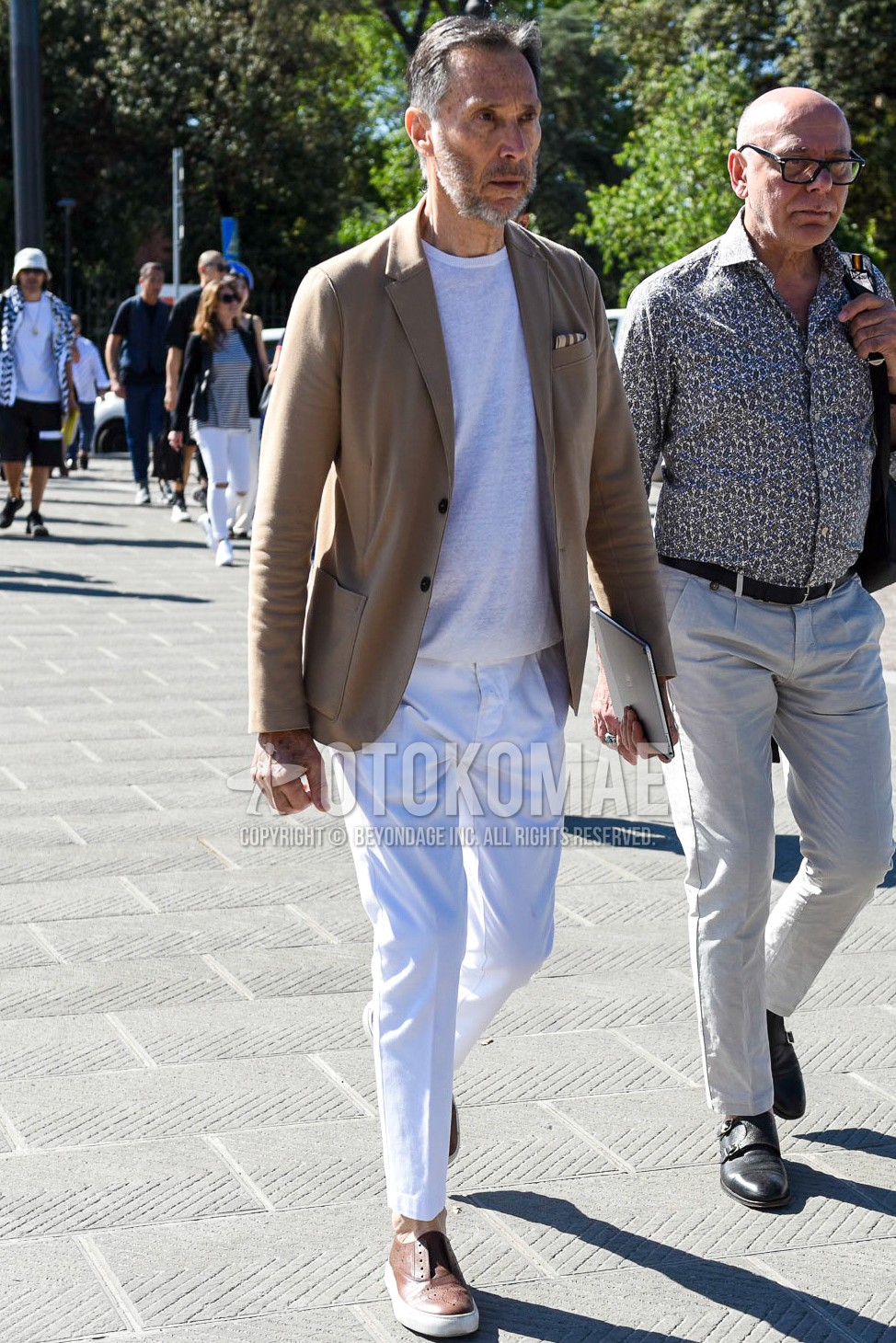 Men's spring summer outfit with beige plain tailored jacket, white plain t-shirt, white plain cotton pants, brown low-cut sneakers.