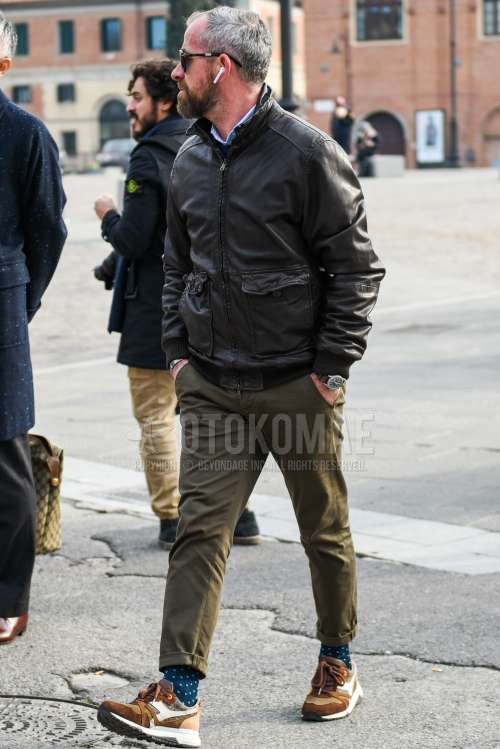 黒無地のサングラス、黒無地のレザージャケット(ライダース以外)、黒無地のミリタリージャケット(MA-1、M-65以外)、オリーブグリーン無地のチノパン、ネイビーソックスのソックス、ブラウンローカットのスニーカーを合わせた秋冬のメンズコーデ・着こなし。