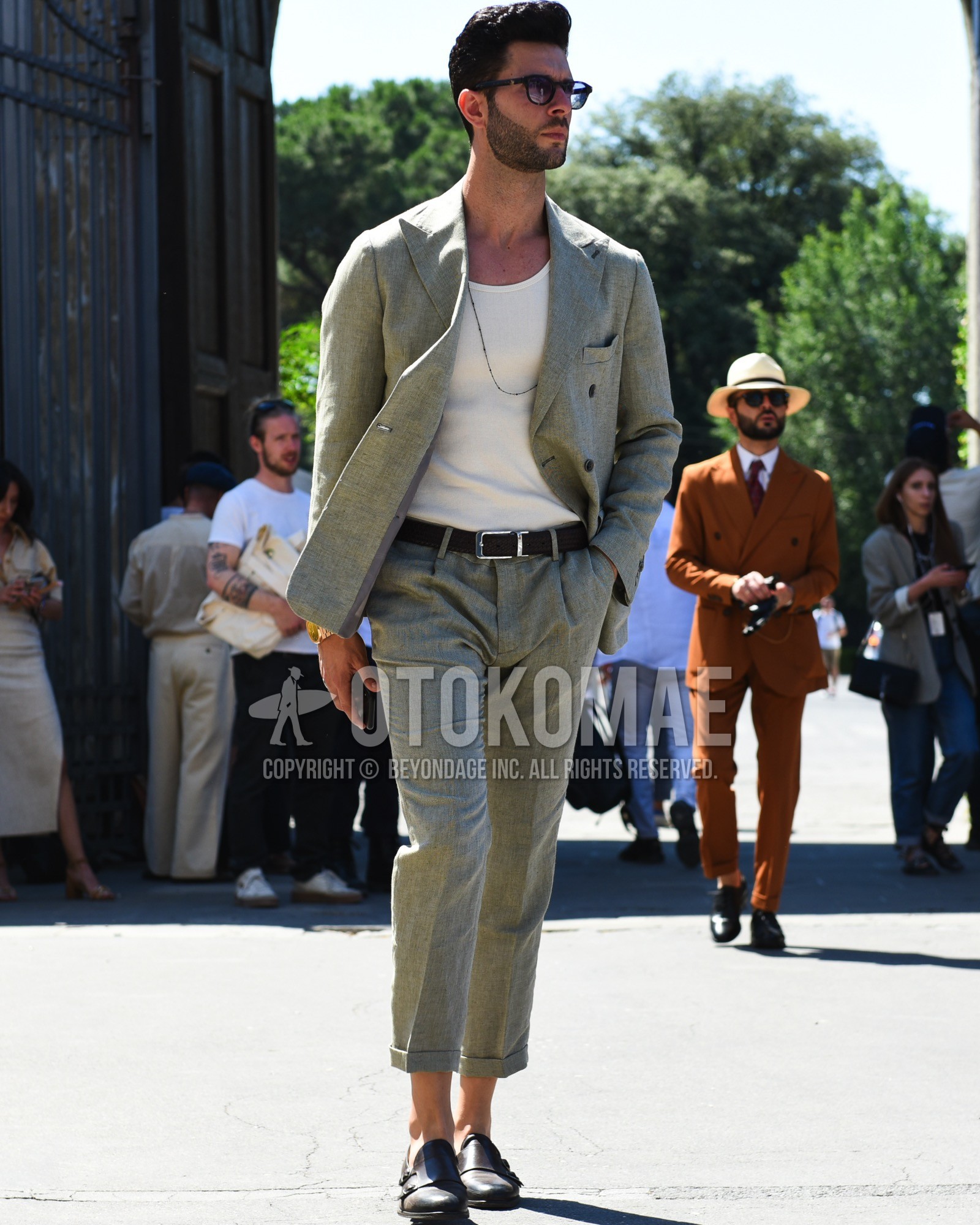 Men's spring summer outfit with black tortoiseshell sunglasses, white plain tank top, brown plain leather belt, brown monk shoes leather shoes, gray plain suit.