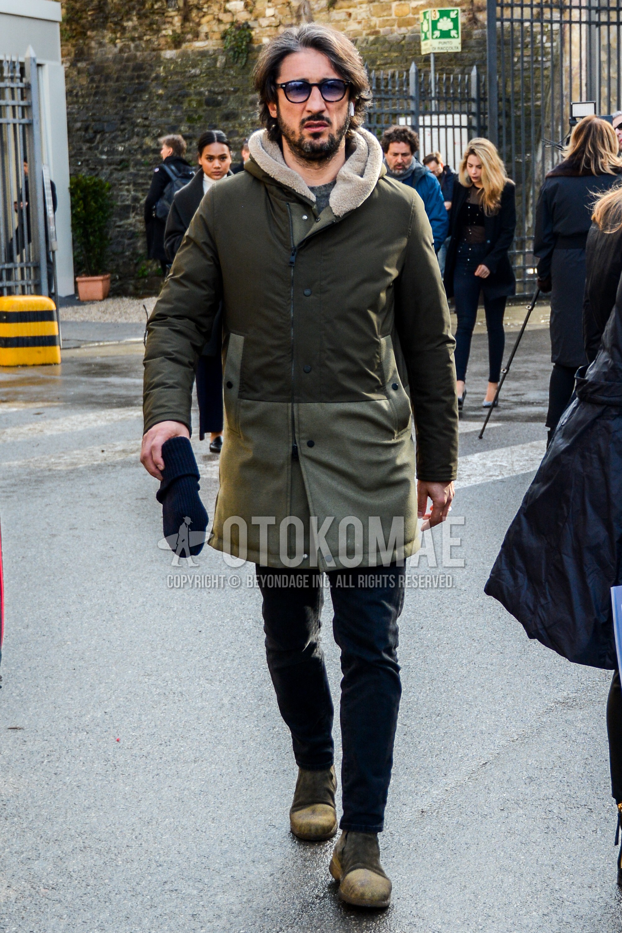 Men's winter outfit with plain sunglasses, olive green plain hooded coat, black plain cotton pants, brown  boots.