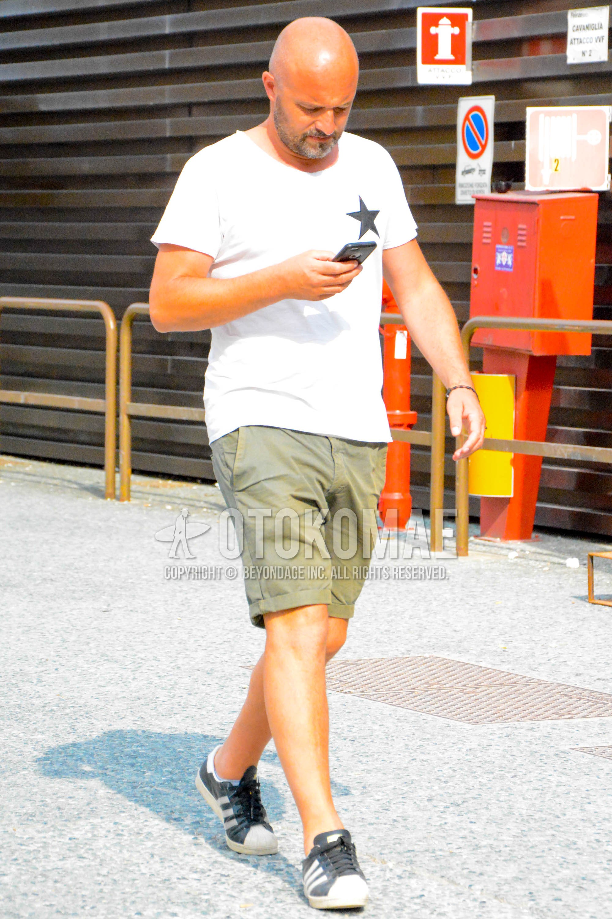 Men's summer outfit with white tops/innerwear t-shirt, olive green plain short pants, black low-cut sneakers.