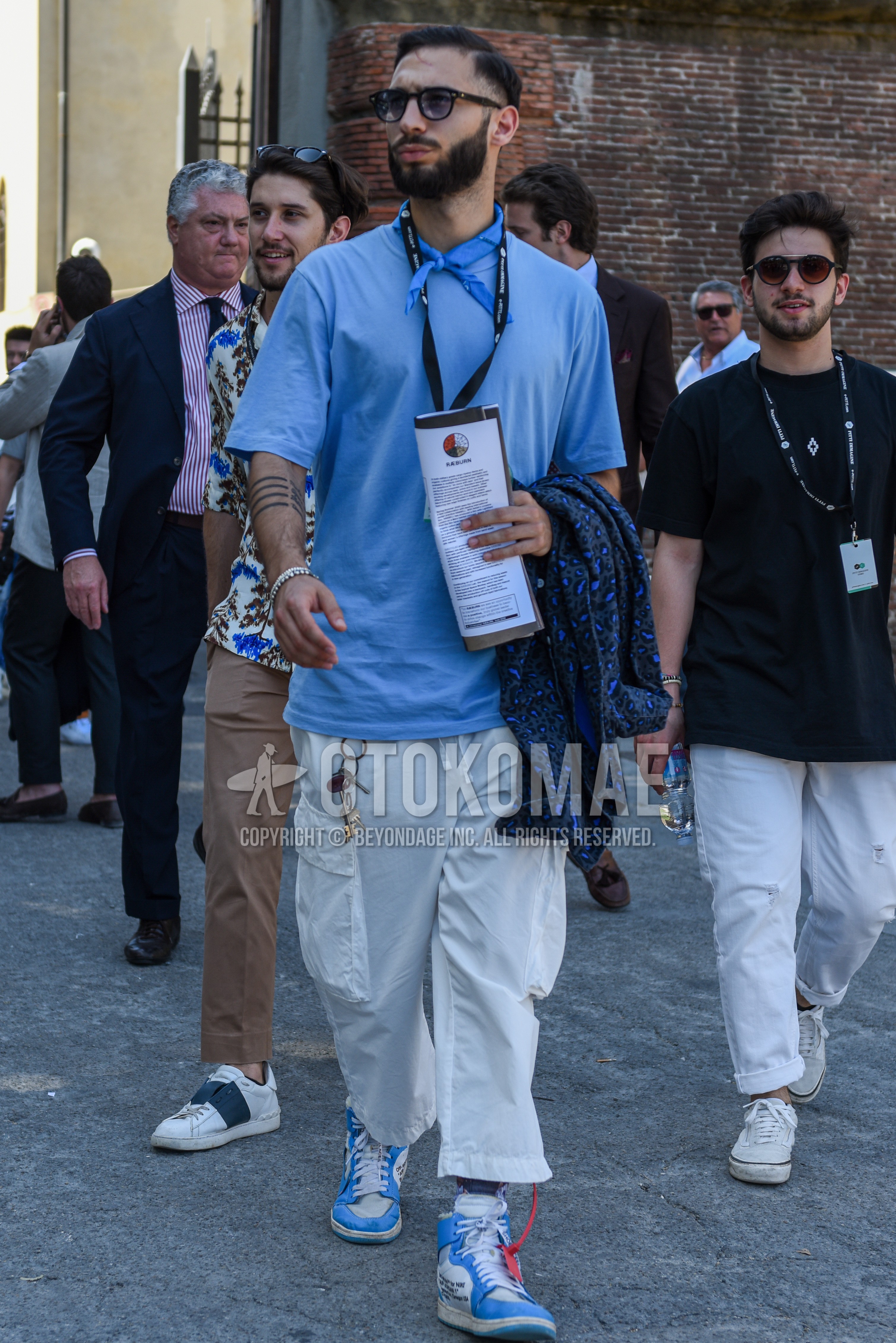 Men's summer outfit with black plain sunglasses, light blue plain bandana/neckerchief, light blue plain t-shirt, white plain cargo pants, light blue white high-cut sneakers.