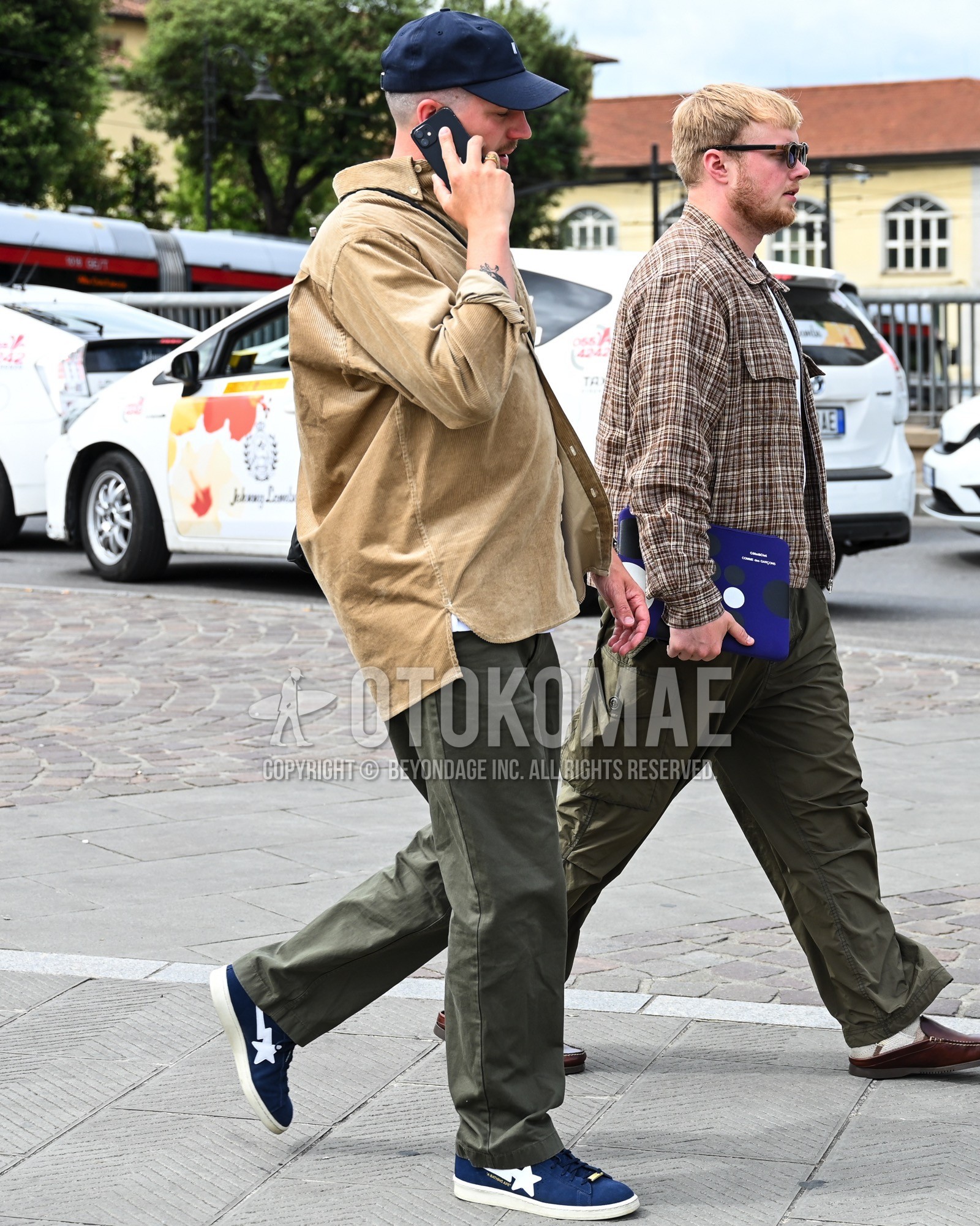 Men's spring summer autumn outfit with navy one point baseball cap, beige plain shirt, white plain t-shirt, olive green plain cargo pants, navy low-cut sneakers.