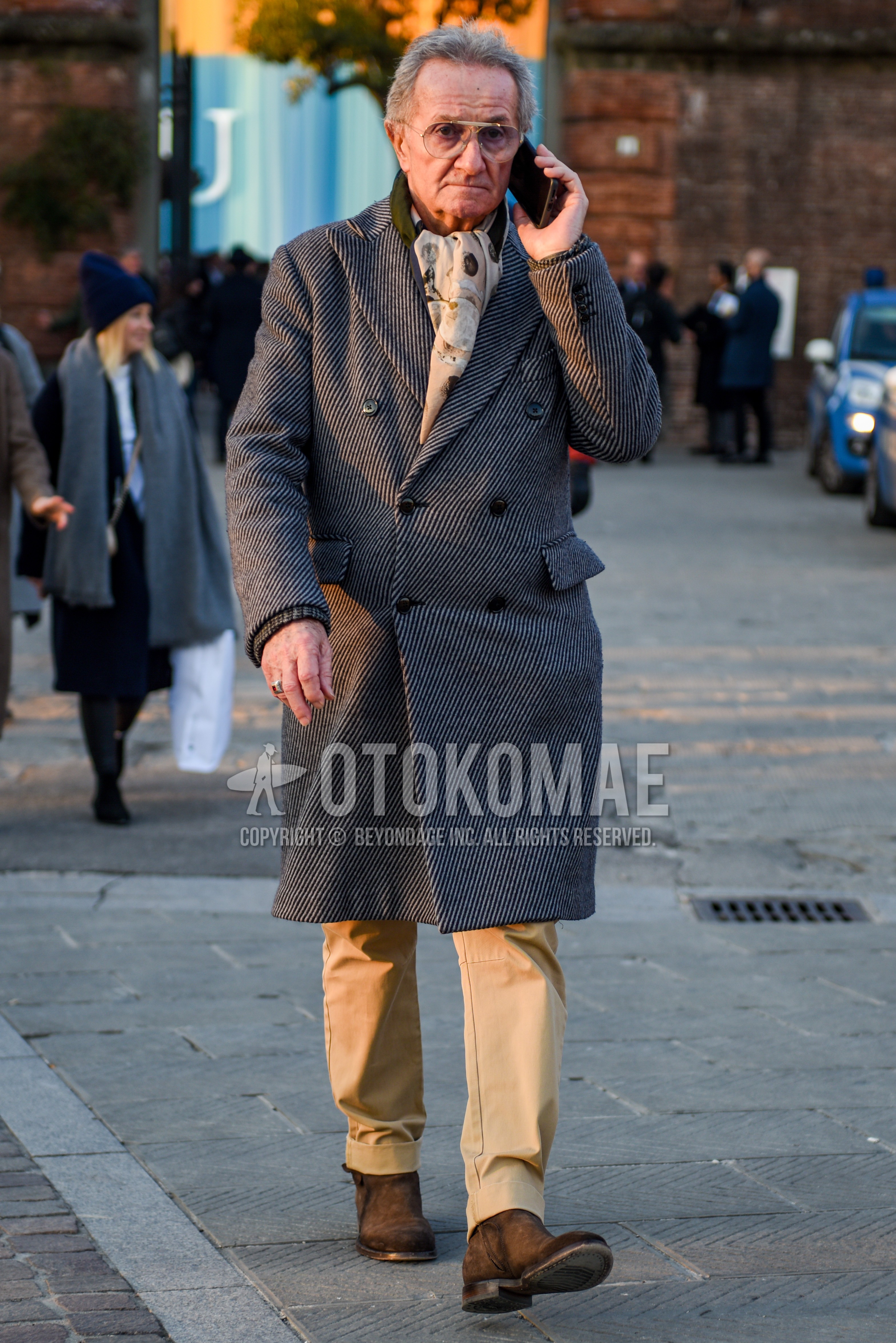 Men's autumn winter outfit with gold plain sunglasses, beige scarf scarf, gray herringbone chester coat, beige plain chinos, brown side-gore boots.