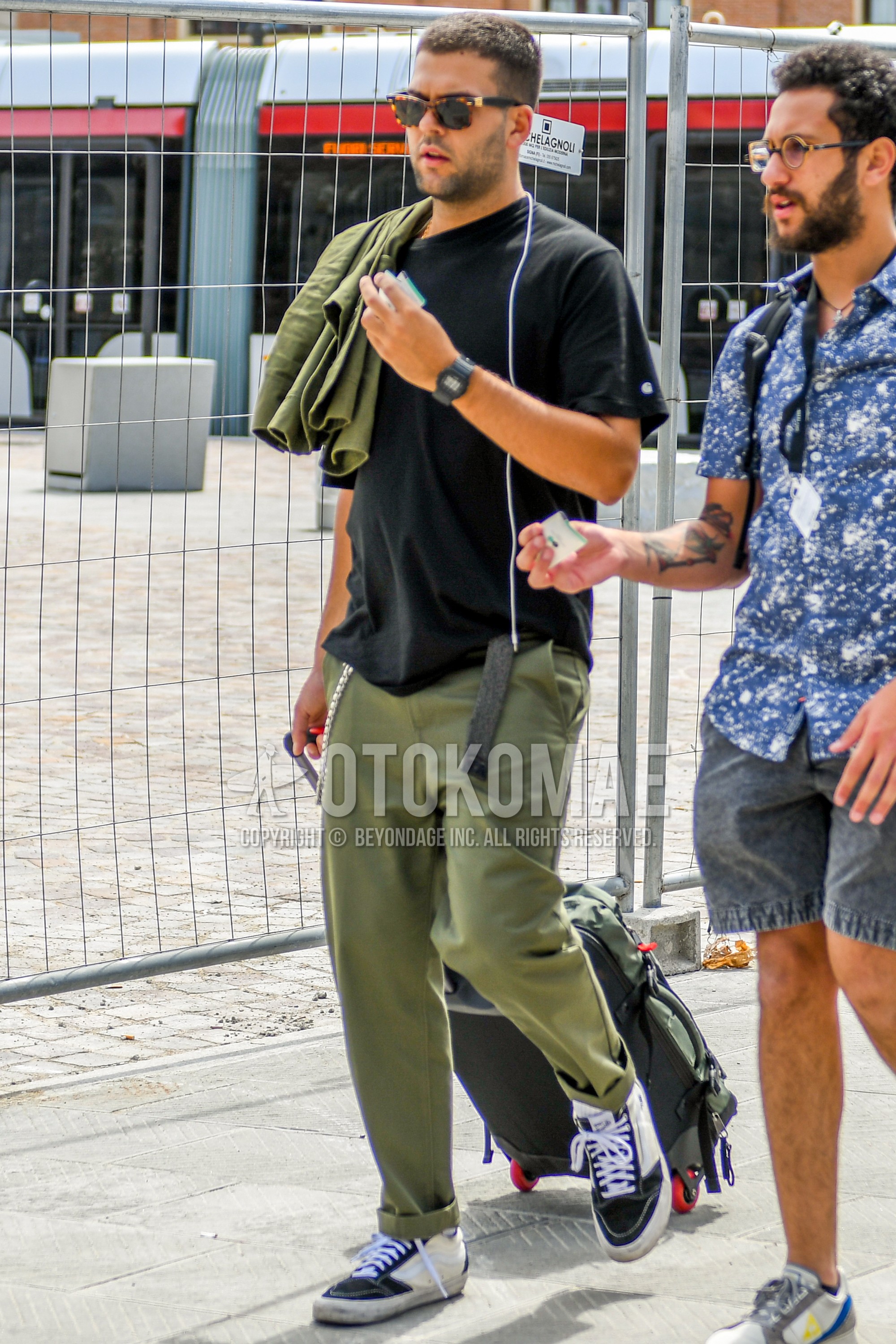 Men's summer outfit with plain sunglasses, black plain t-shirt, dark gray plain tape belt, olive green plain cotton pants, white black low-cut sneakers.
