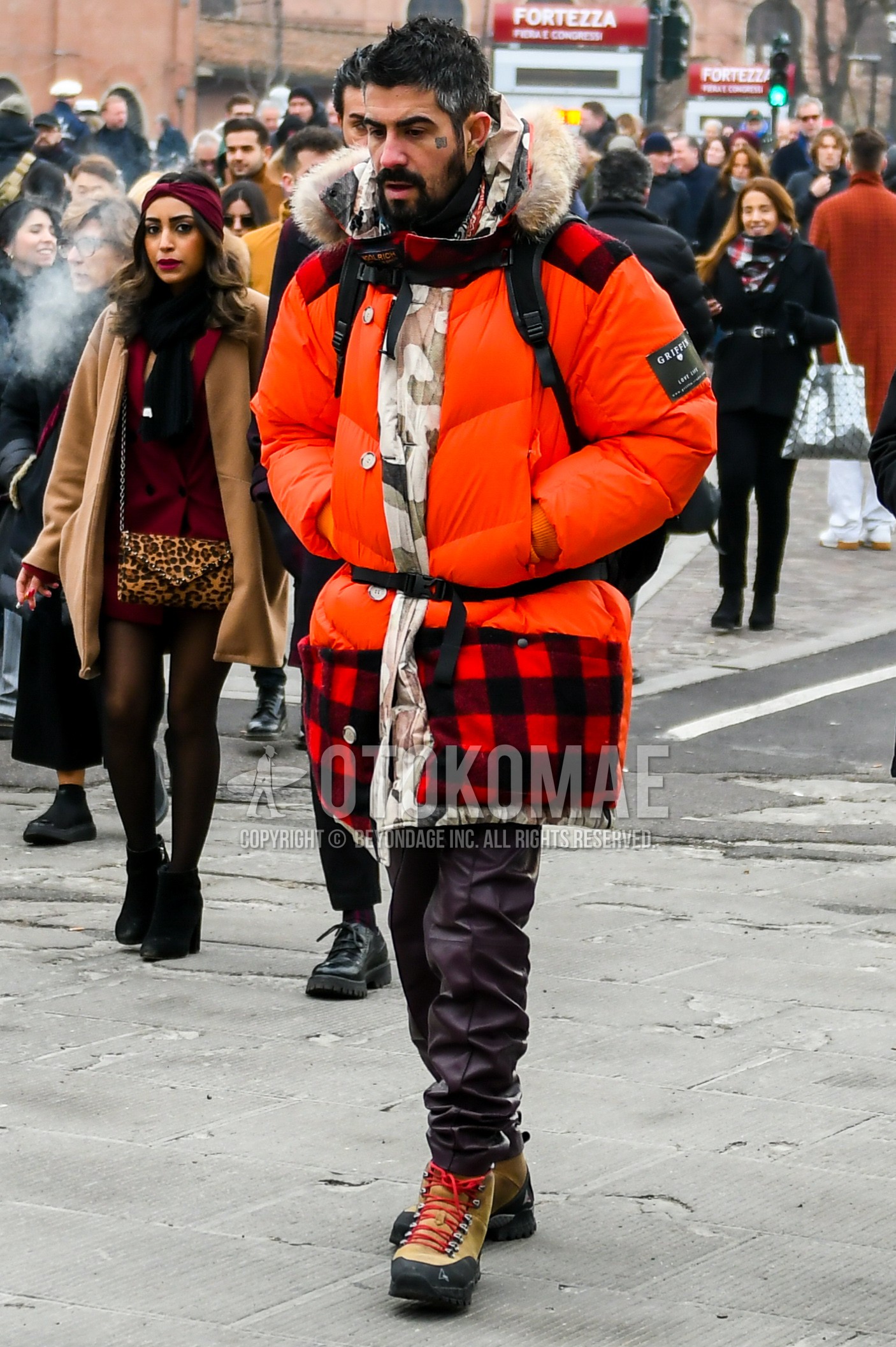 Men's winter outfit with orange plain down jacket, black plain turtleneck knit, dark gray plain bottoms, multi-color  boots.
