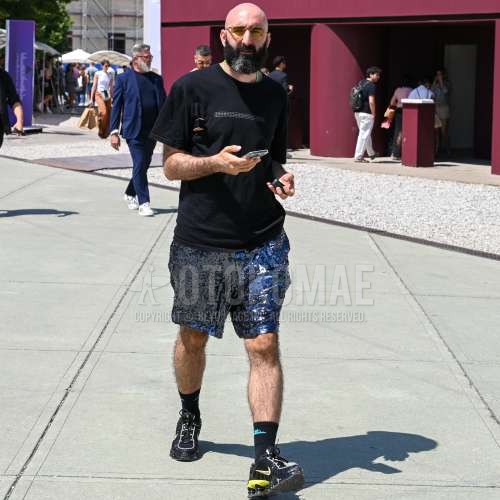 ゴールド無地のサングラス、黒レタードのTシャツ、ブルーボトムスのショートパンツ、黒レタードのソックス、ナイキ　ショックスの黒ローカットのスニーカーを合わせた夏のメンズコーデ・着こなし。