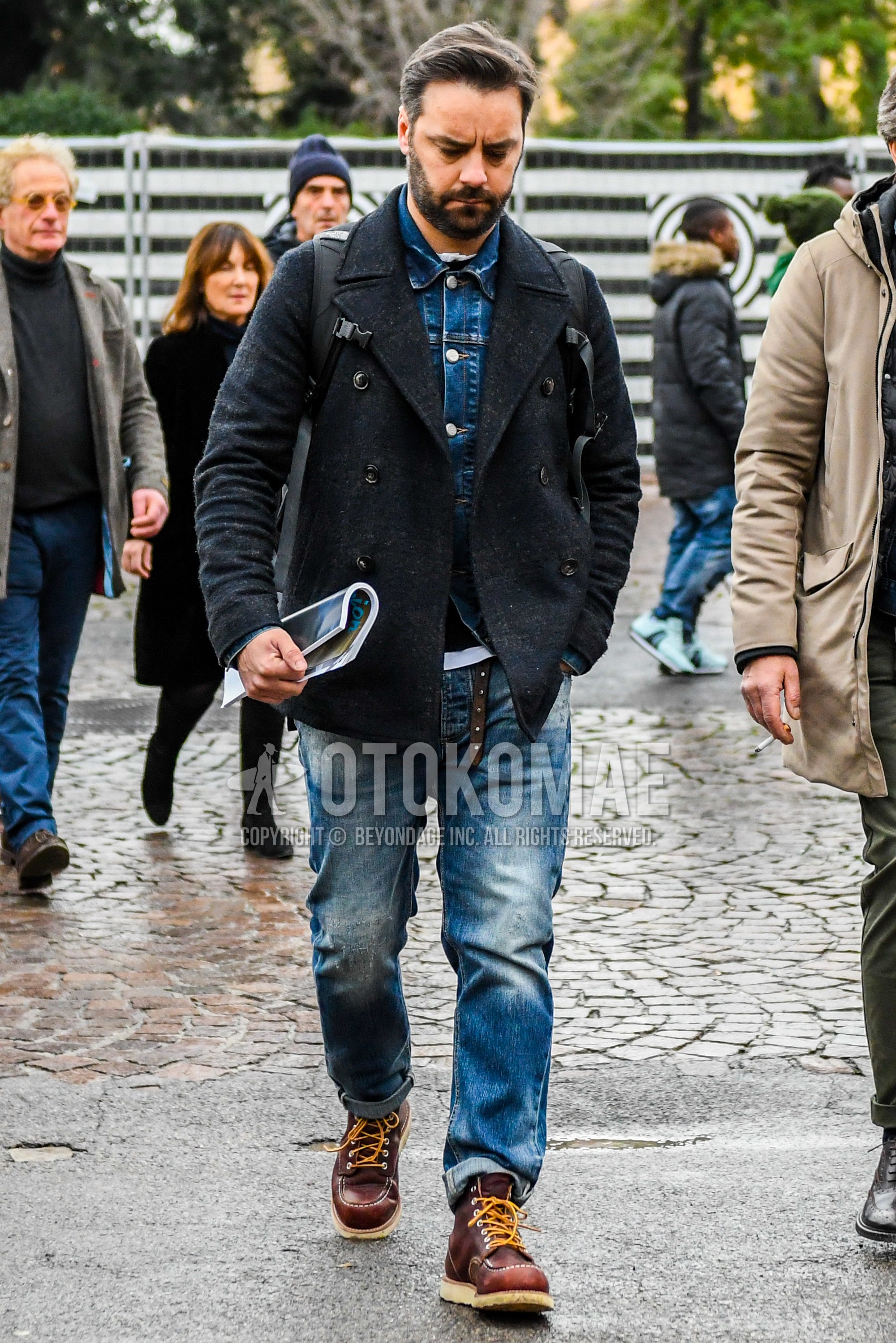 Men's winter outfit with dark gray plain p coat, blue plain denim jacket, blue plain denim/jeans, brown work boots.