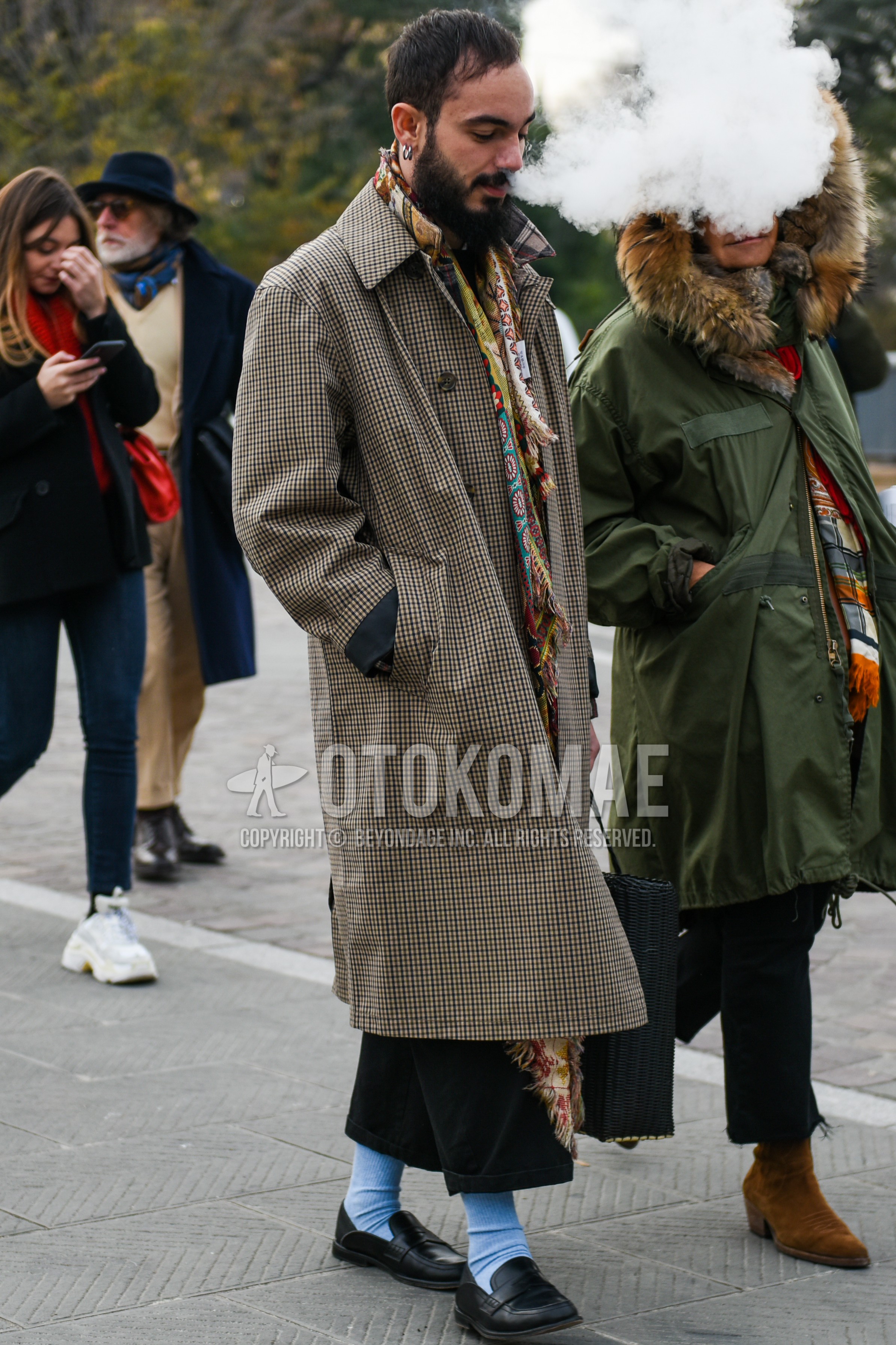 Men's autumn winter outfit with multi-color scarf scarf, beige plain stenkarrer coat, black bottoms wide pants, black plain cropped pants, light blue plain socks, black coin loafers leather shoes.
