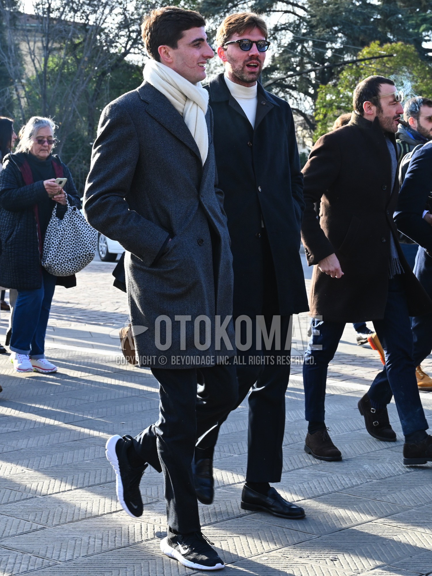 Men's autumn winter outfit with white plain scarf, gray plain chester coat, black plain slacks, black low-cut sneakers.