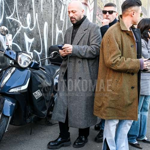 グレー無地のアルスターコート、黒無地のインナーダウン、黒無地のタートルネックニット、黒無地のコットンパンツ、黒コインローファーの革靴を合わせた冬のメンズコーデ・着こなし。